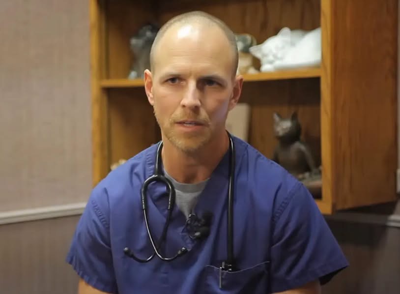 Bryan Schmidt appears in blue scrubs with a stethoscope in an older video. Although dressed like a veterinarian, he was identified in the family's archived business materials as the manager of Northern Illinois Cat Clinic. | Source: Facebook / Carlos Moreno Reporta.
