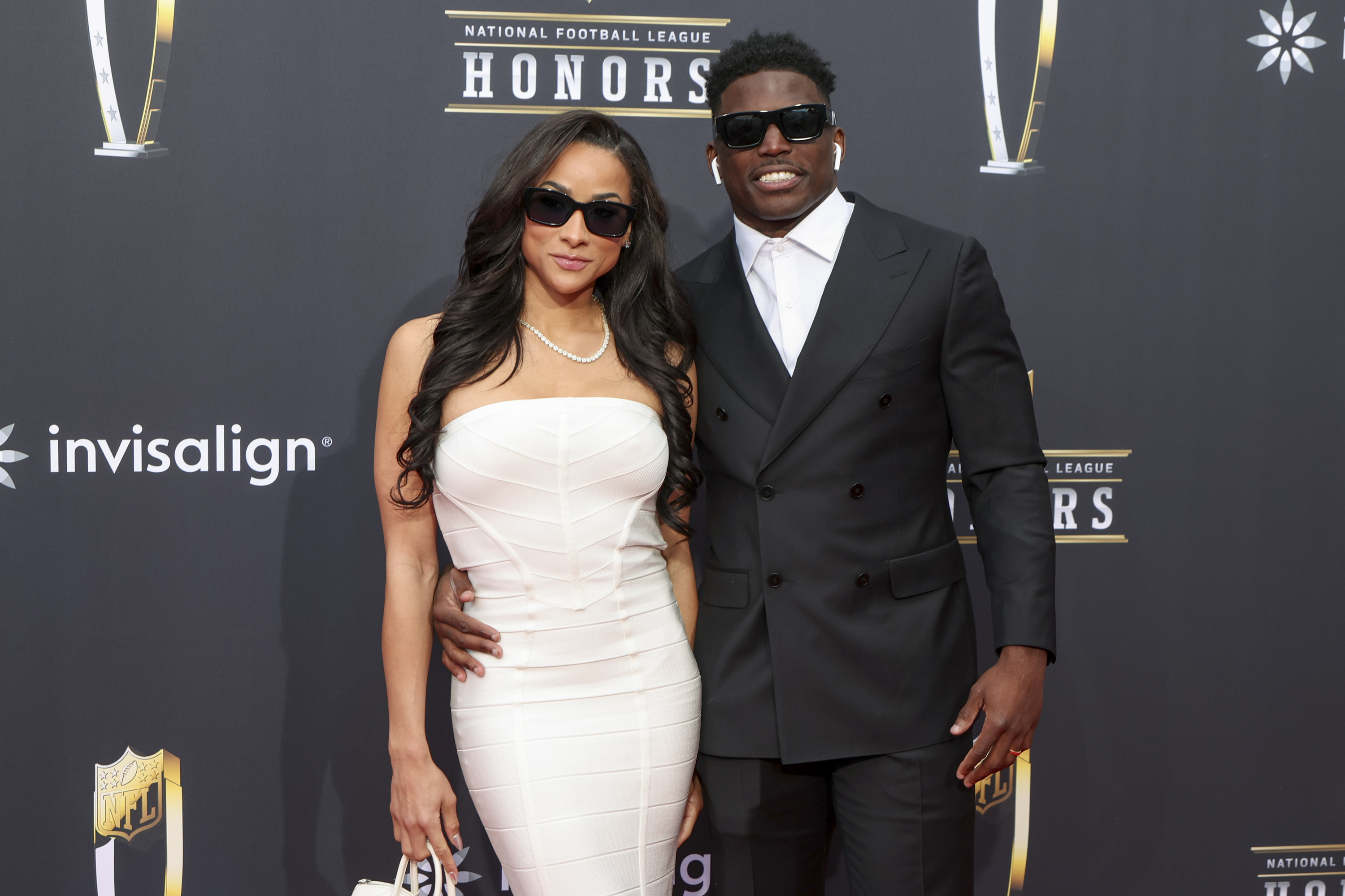 Keeta Vaccaro and Tyreek Hill pose together on the red carpet at the 13th Annual NFL Honors, with Vaccaro wearing a strapless white gown, a pearl necklace, and dark sunglasses as Hill complements her in a black double-breasted suit and sunglasses. The couple attended the star-studded football awards ceremony at Resorts World Theatre in Las Vegas, Nevada, on February 8, 2024.