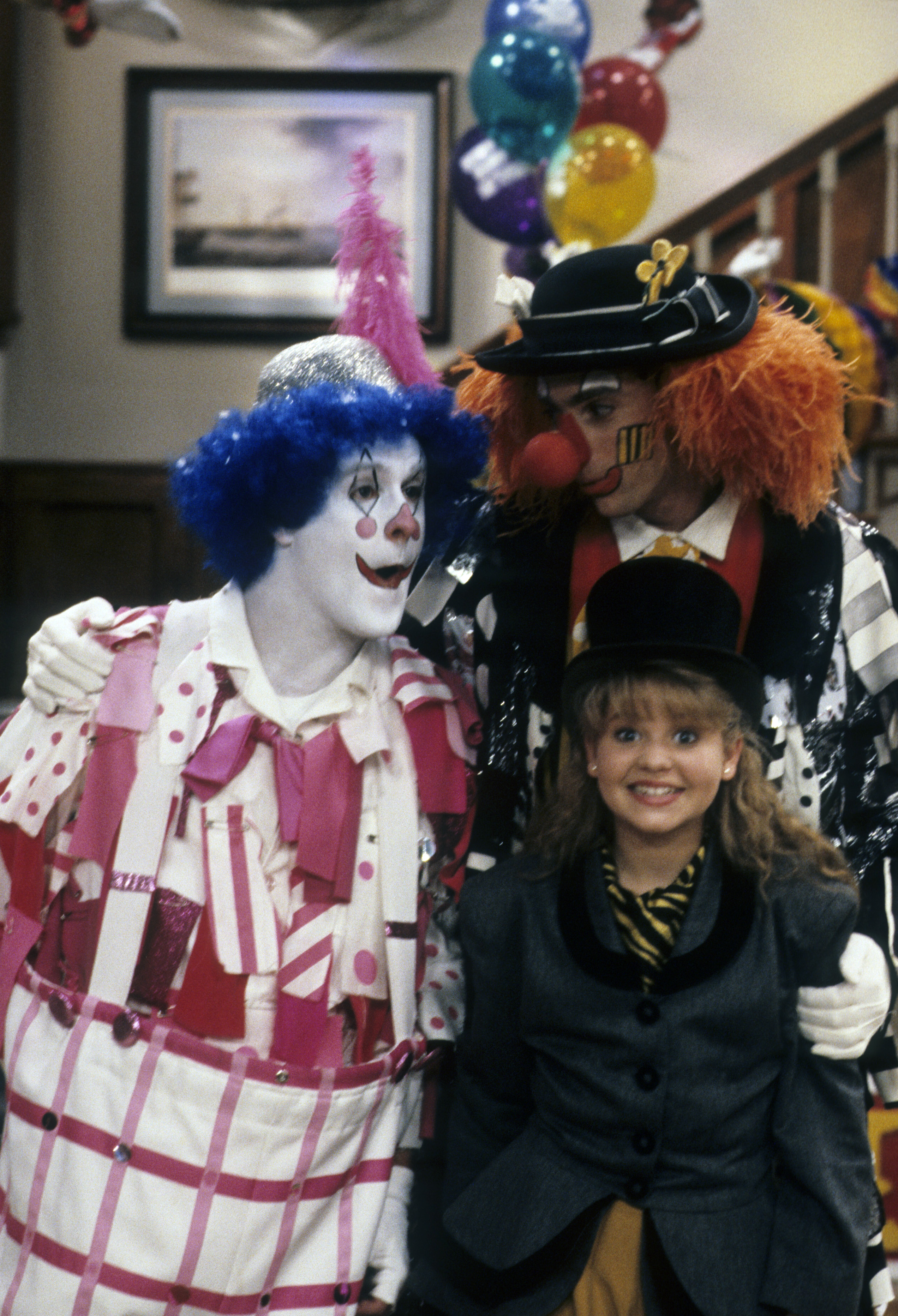 Candace Cameron Bure beams in a top hat and circus ringmaster-style jacket between Dave Coulier and Bob Saget in the 1989 "Full House" episode "The Greatest Birthday on Earth". Cast as eldest daughter D.J. Tanner at age 10, Cameron Bure brought infectious warmth and relatable teenage charm to the role, helping establish the heart of the sitcom while launching a versatile screen career that would continue to flourish for decades.
