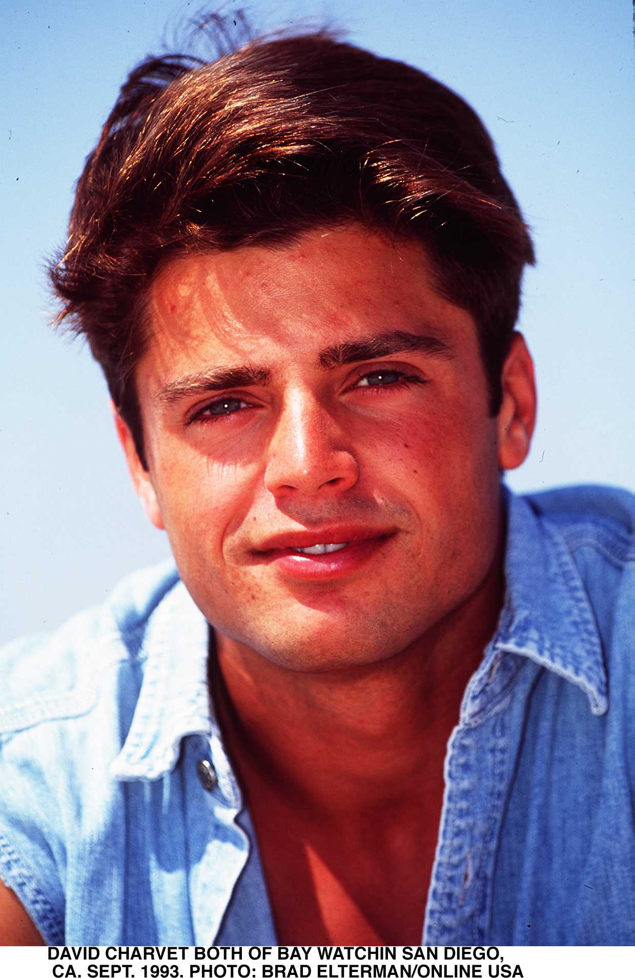 Taking a break from filming "Baywatch" in San Diego on September 1, 1993, David Charvet posed for a sunlit close-up that captured his youthful appearance during the show's successful run. Dressed casually in a light denim shirt, the actor sported the thick brown hair and tanned complexion familiar to viewers. At the time, his portrayal of Matt Brody was making him an increasingly recognizable television face.