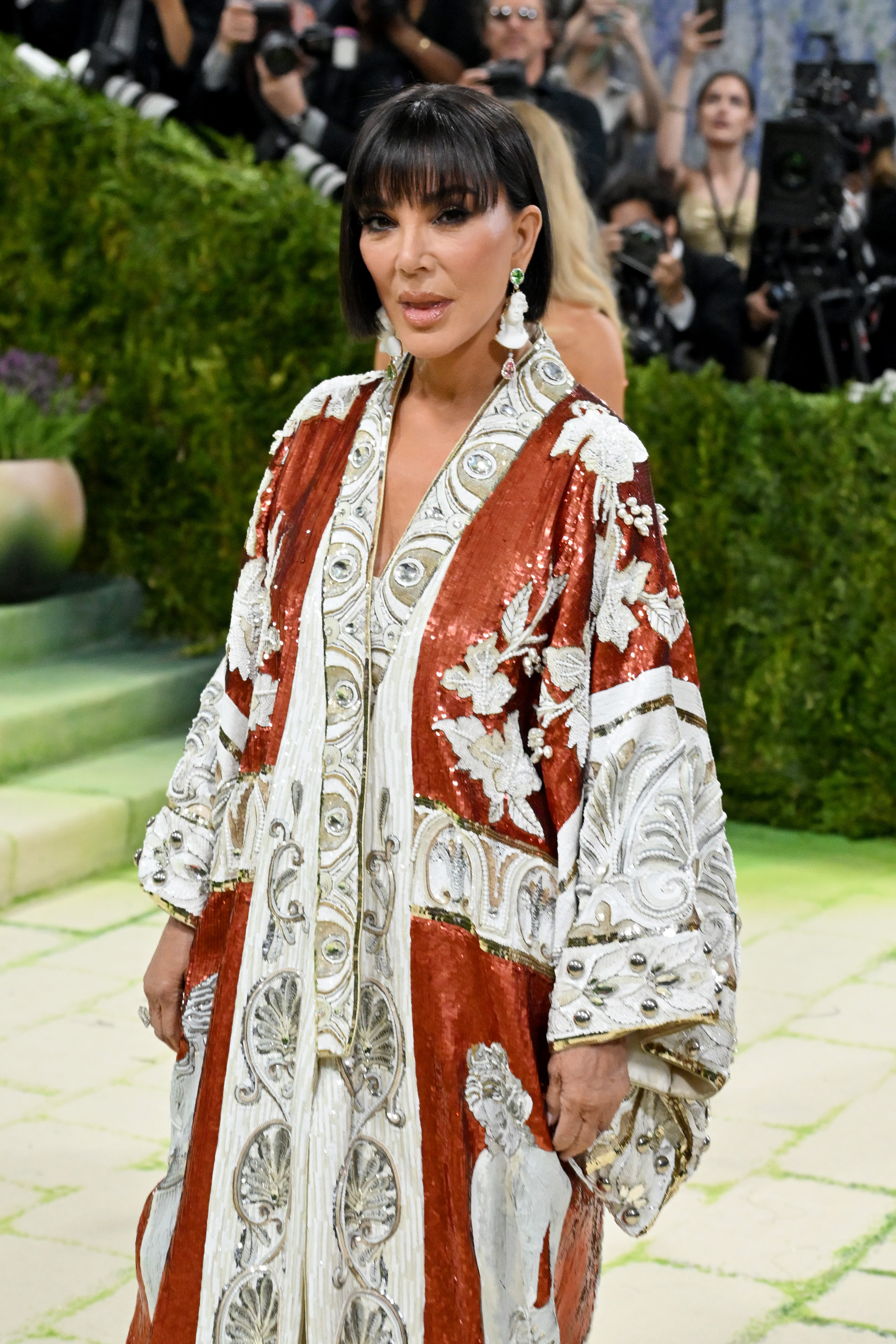Kris Jenner poses for photographers in her ornate red-and-white embellished ensemble at the Met Gala. | Source: Getty Images
