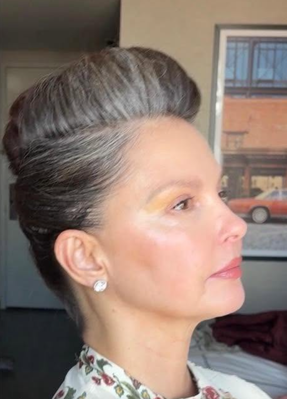 Ashley Judd shows off her silver-streaked hair in an elegant updo in a 2025 photo. The side profile highlights the contrast between her gray roots and darker hair. | Source: Facebook/AshleyJuddOfficial
