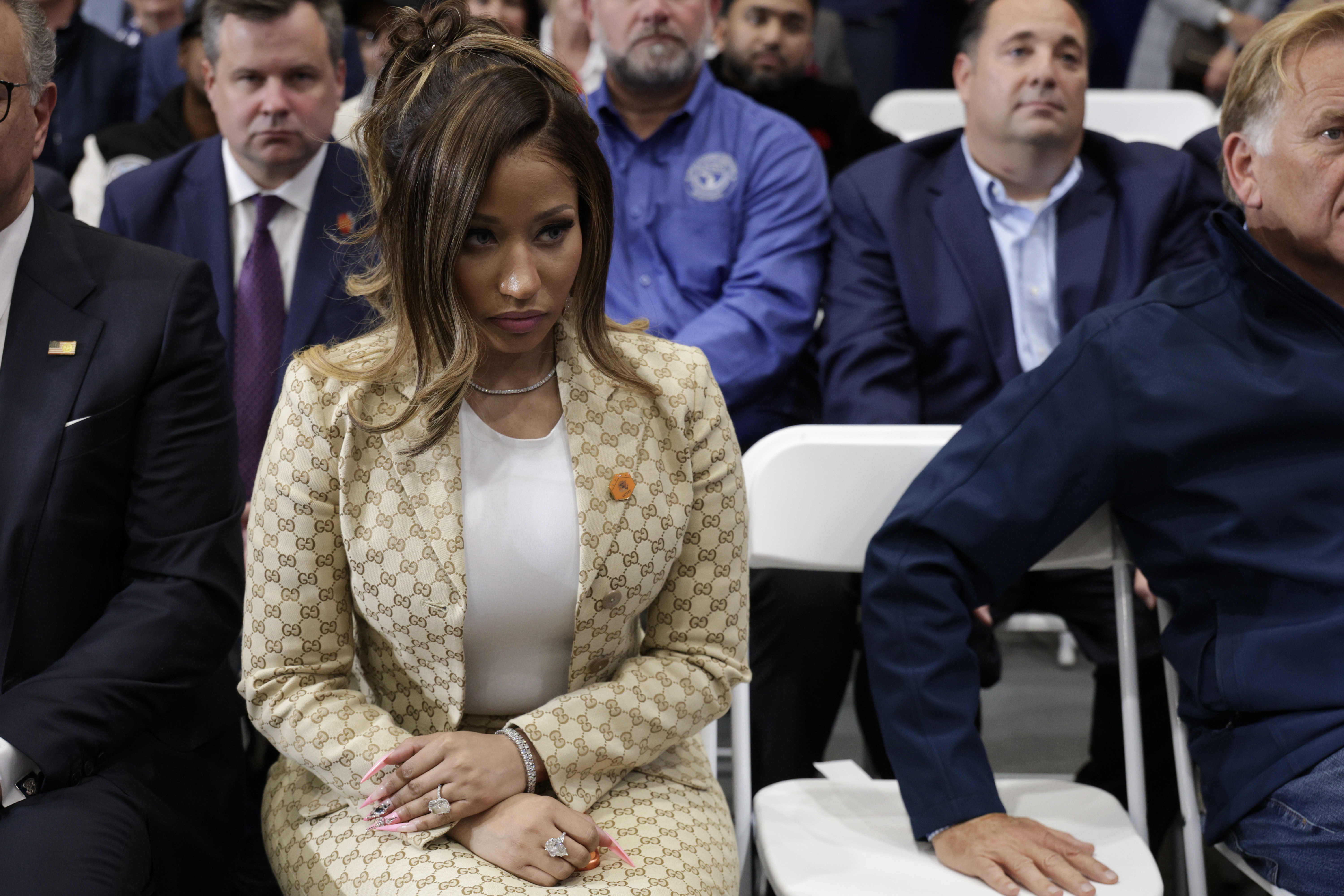 Nicki Minaj sits quietly among other guests at the rally, her hands resting in her lap as she looks toward the stage — a more reserved moment from an appearance that later sparked unexpected headlines. | Source: Getty Images
