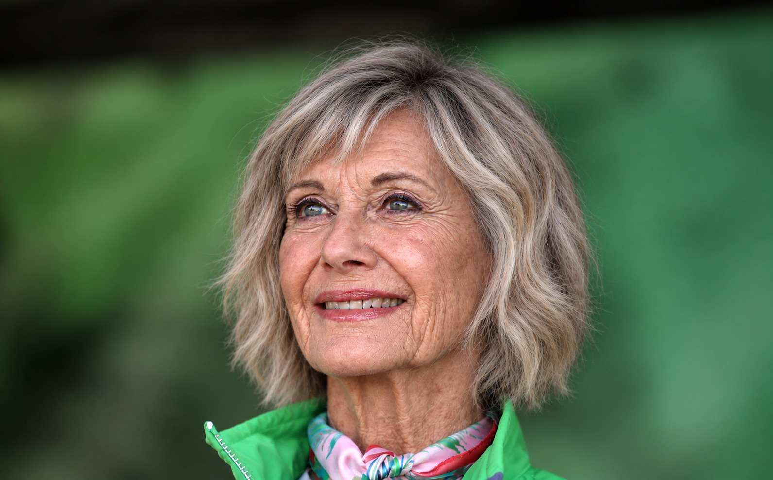 AI-generated impression. At 77, the rendering presents an older Olivia outdoors with more visible signs of age and the same bright expression associated with her public image. The portrait is fictional, but the extra year it imagines carries an undeniable emotional weight. | Source: Chat GPT