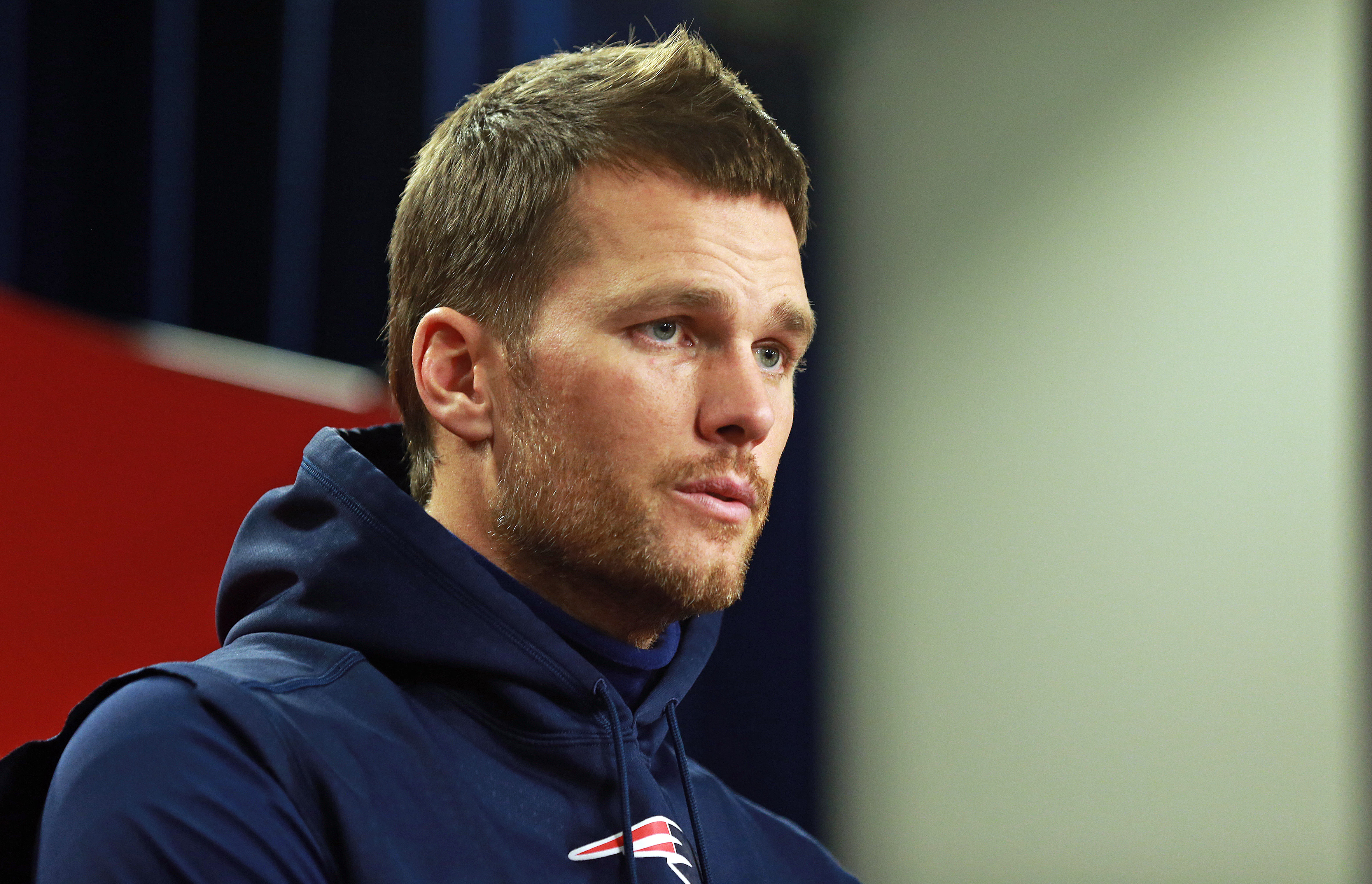 Tom Brady, sporting a fuller beard than usual, speaks at a press conference at Gillette Stadium. His rugged look adds a new edge to his trademark composure.