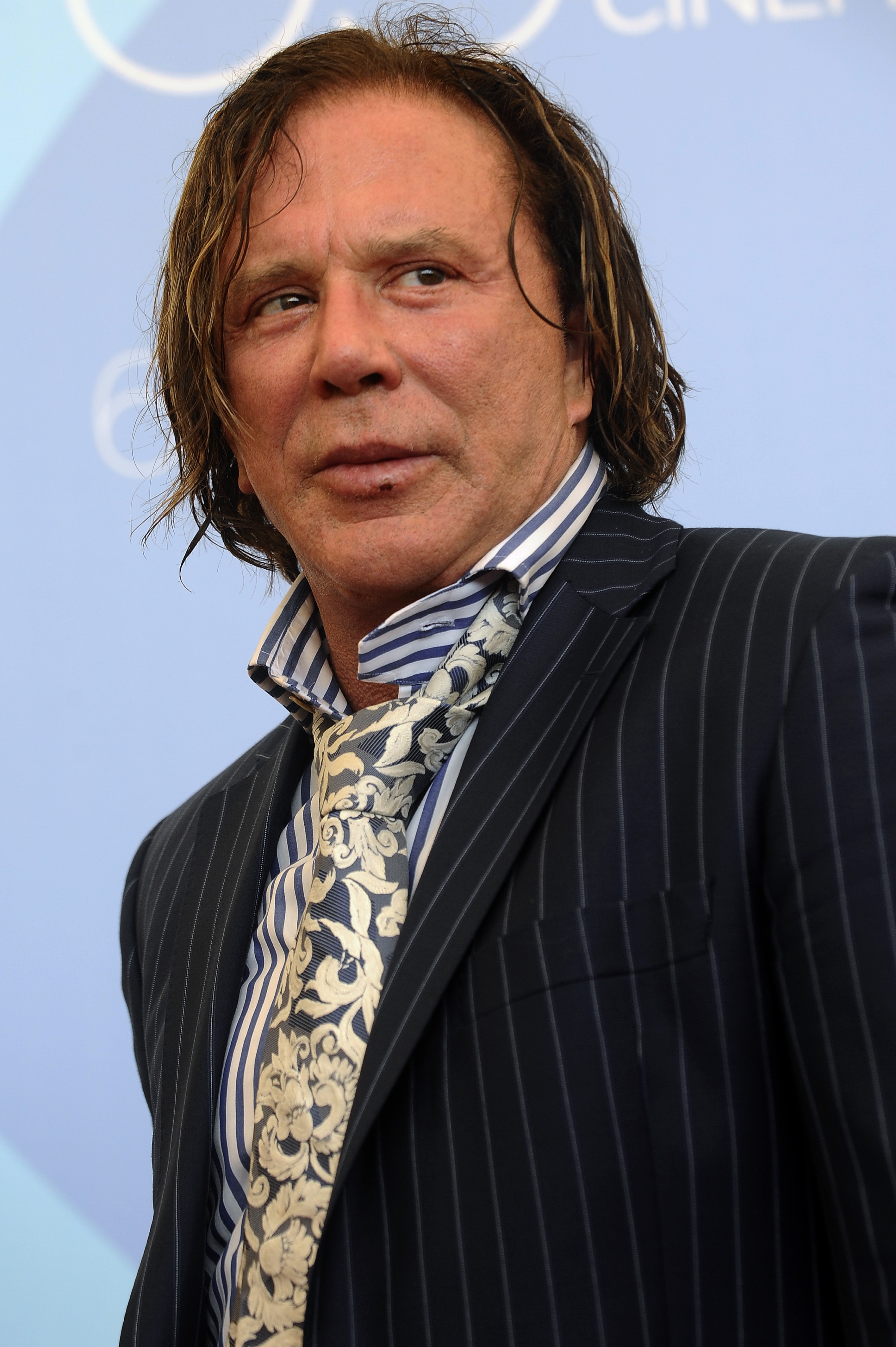 Mickey Rourke attends the photocall for "The Wrestler" at the 65th Venice International Film Festival. Clad in a pinstripe suit with a bold patterned tie, he exudes rugged charisma with his intense gaze and tousled hair.