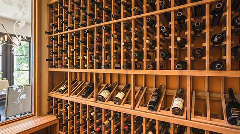 The climate-controlled, walk-in wine cellar features custom light-wood racking with dedicated horizontal storage, angled display shelves for vintage bottles, and an etched-glass viewing window. | Source: YouTube/Taste of Country