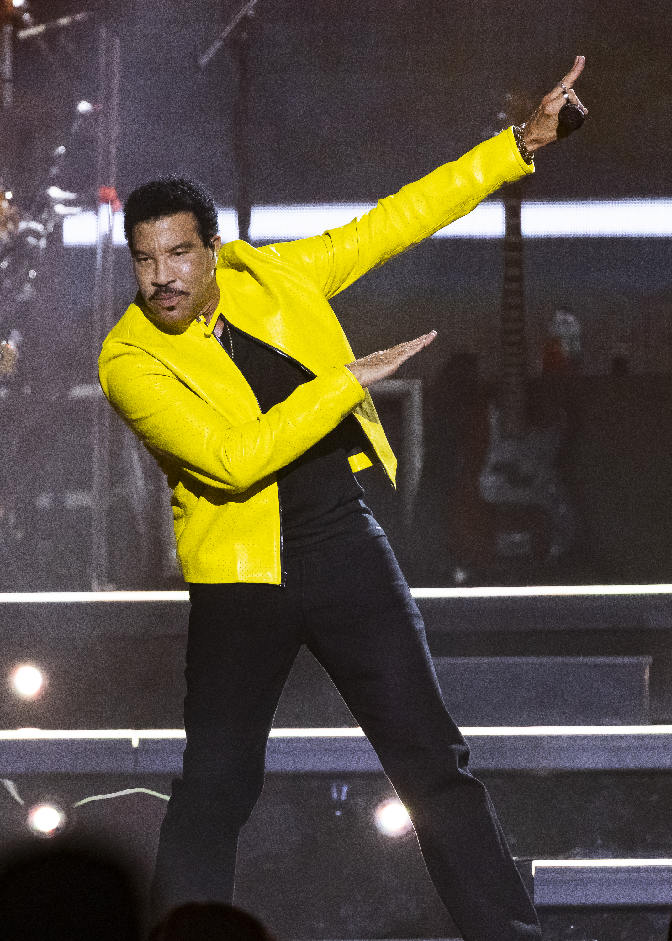 Lionel Richie performed at Little Caesars Arena in Detroit on July 1, 2026, during his summer tour with Earth, Wind & Fire. Wearing a bright yellow jacket, he struck an animated pose onstage nearly two months before his St. Louis hospitalization. | Source: Getty Images