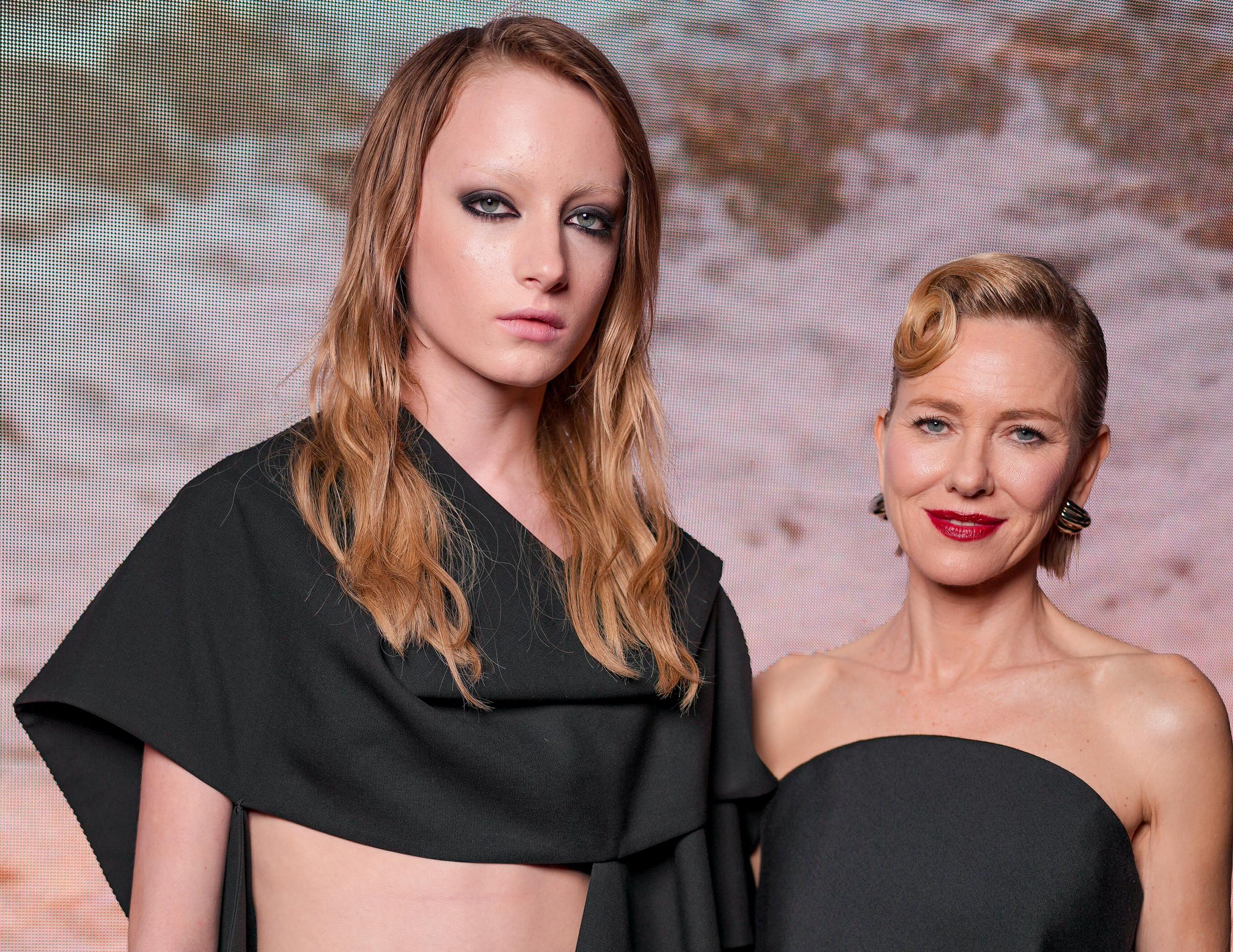 Kai Schreiber and Naomi Watts pose side by side in a striking mother-daughter moment. Kai looks ahead with a serious expression while Watts smiles softly toward the camera.