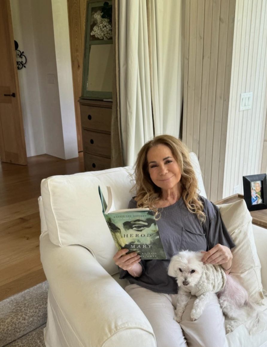 Kathie Lee Gifford enjoys a quiet moment at home, relaxing in a cozy white armchair with a book and her beloved little dog by her side. | Source: Instagram @kathielgifford.