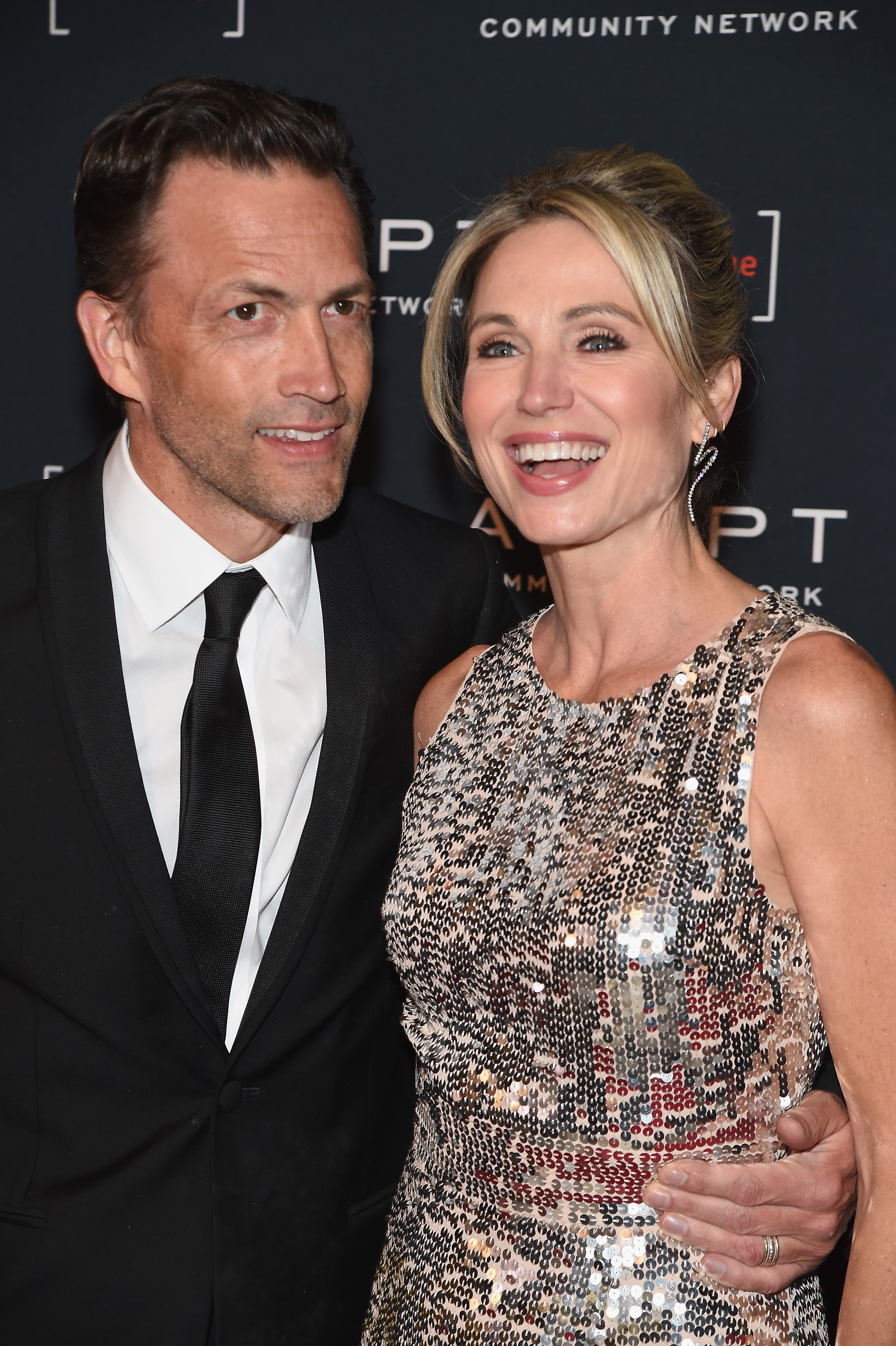Andrew Shue and then-wife Amy Robach smile closely together at the 2022 ADAPT Leadership Awards gala at Cipriani 42nd Street in New York City on March 10, 2022. Attending the event where Robach was honored, the former couple coordinated in evening wear, with the journalist dazzling in a sleeveless champagne sequined cocktail dress while Shue supported her in a black tuxedo and satin necktie. | Source: Getty Images