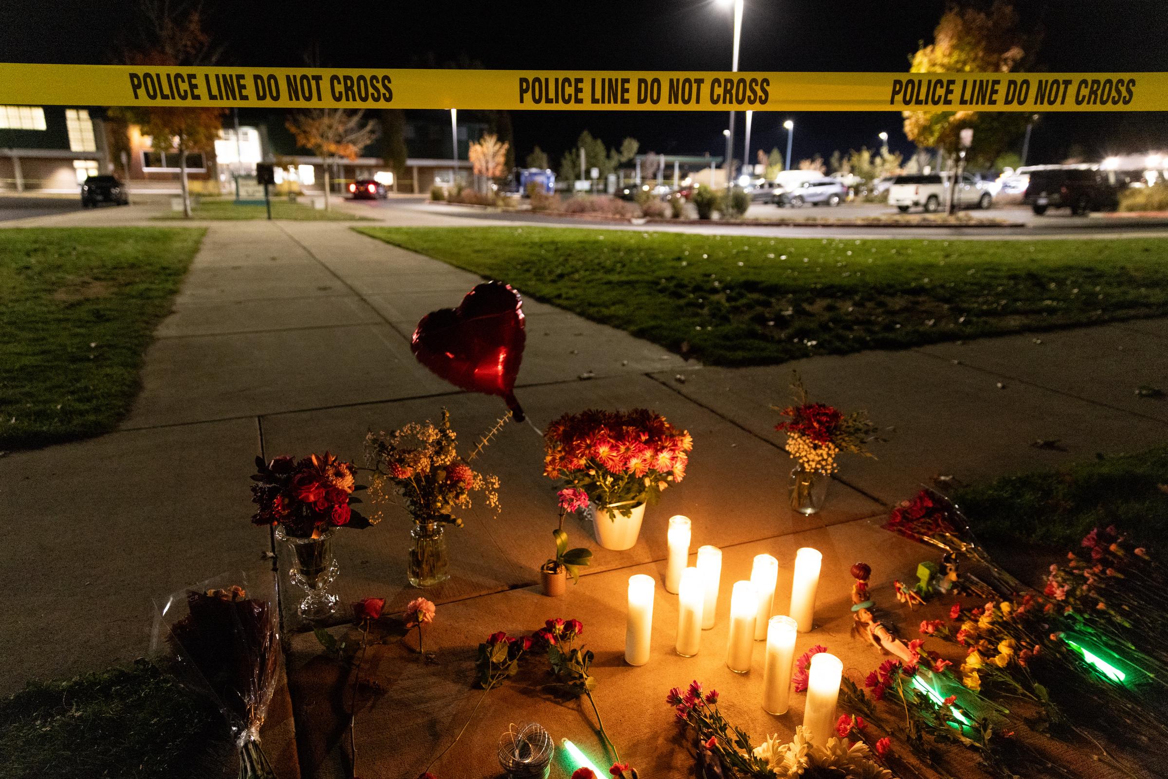 Flowers, candles, and other tributes form a memorial near Silver Rail Elementary School behind a police line.