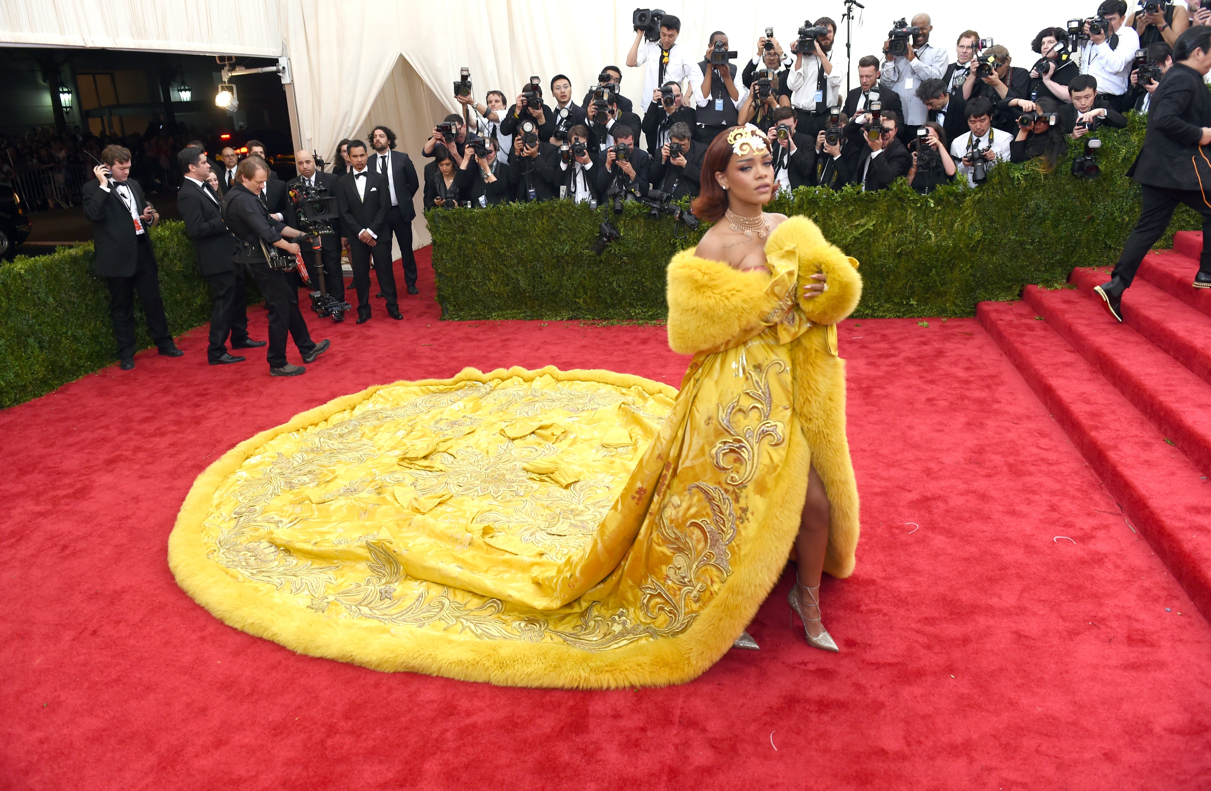 Rihanna delivered one of the most unforgettable red carpet moments in fashion history at the Metropolitan Museum of Art's Costume Institute Gala benefit celebrating "China: Through the Looking Glass" on May 4, 2015, in New York City. The music and style icon commanded the red carpet in Guo Pei’s imperial yellow haute couture cape, complete with opulent gold-thread embroidery, plush fur trim, and a massive circular train that fanned out majestically before the rows of photographers. | Source: Getty Images