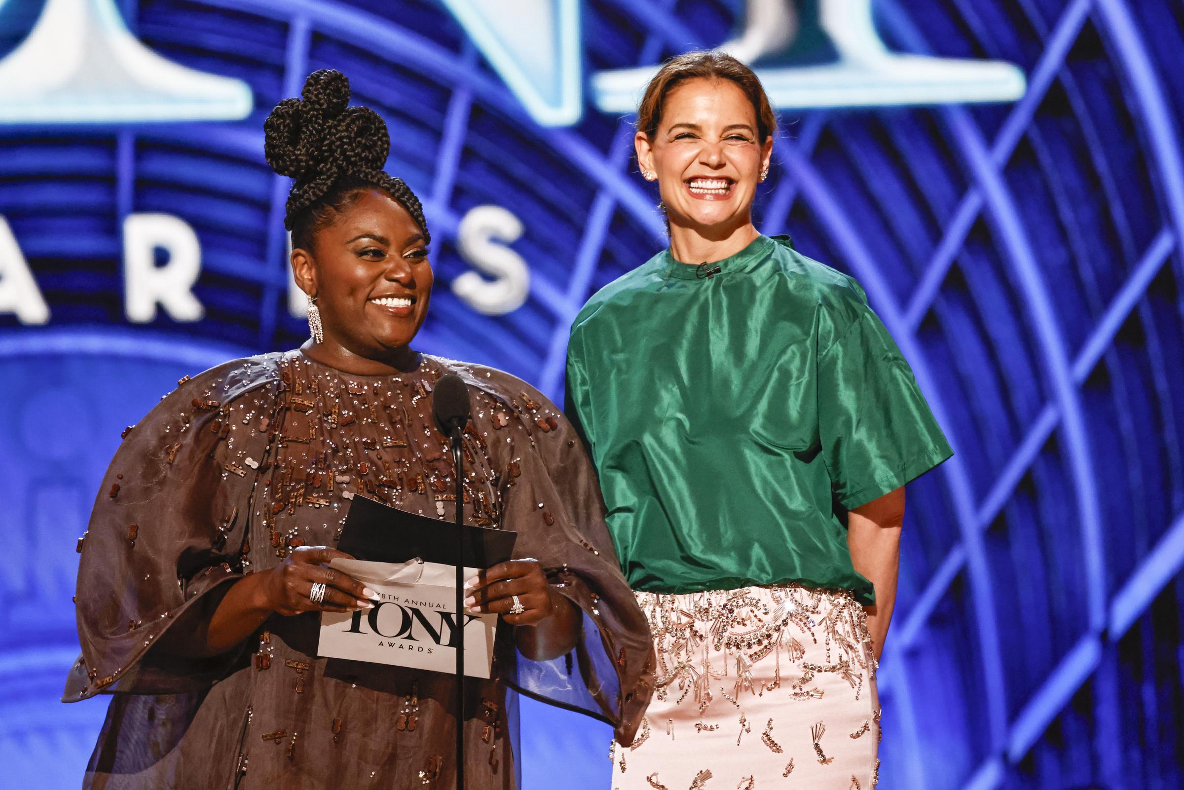 Radiating joy, Katie Holmes shares a laugh with Danielle Brooks while presenting live on the Tony Awards stage. The two delivered one of the evening’s standout presenting moments with charm and charisma.