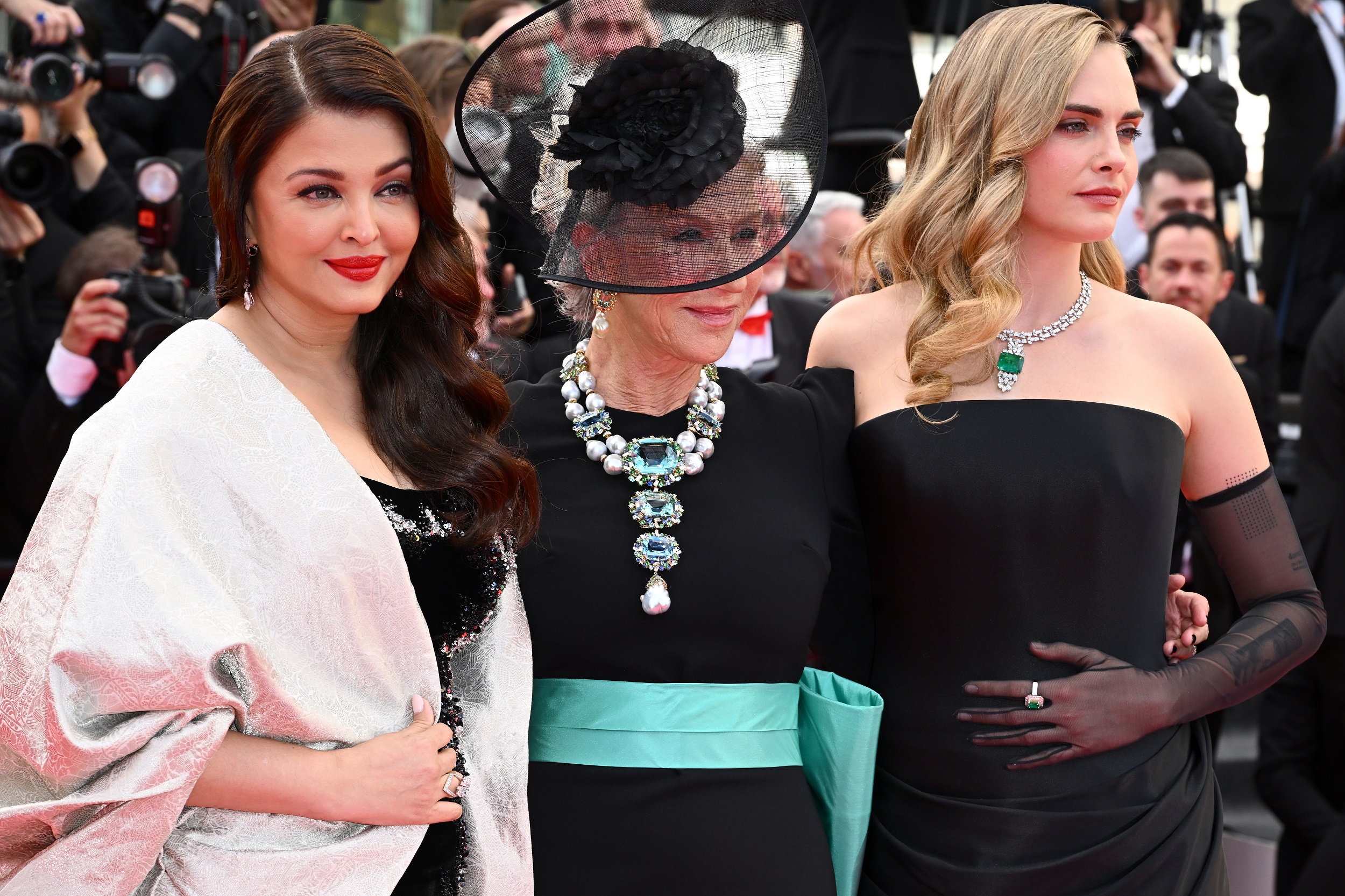 Mirren stands flanked by Aishwarya Rai and Delevingne in a trio of glamour. Rai’s look is all elegance with her sweeping ivory shawl draped over a sequined black gown, her bold red lips and side-swept waves completing the timeless effect. Yet even amid the striking trio, Mirren’s ornate necklace remains the undeniable centerpiece.