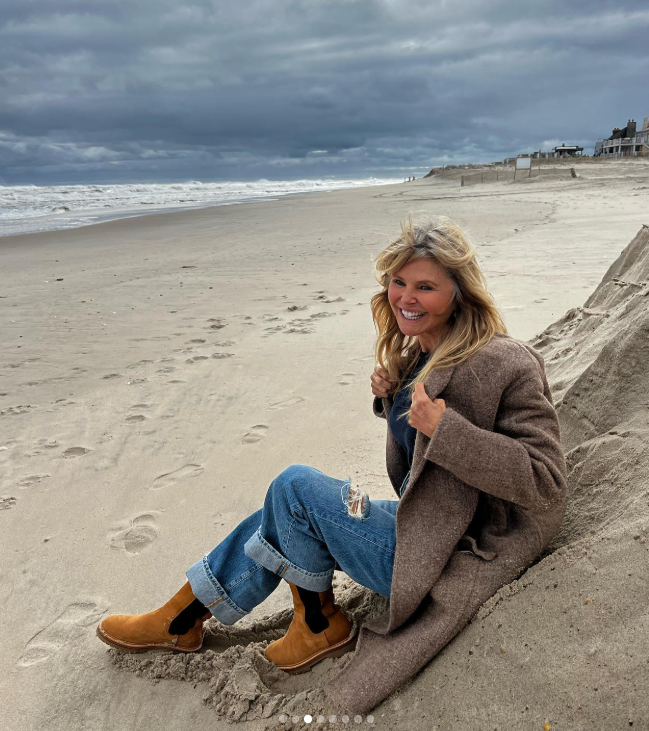 Sitting on the sand in a brown coat and cuffed jeans, Brinkley shows off her windswept hair against a cloudy sky. She compared her emerging gray strands to the ocean's waves, saying she might wait until her hair resembled the silver whitecaps before embracing the change. | Source: Instagram/christiebrinkley