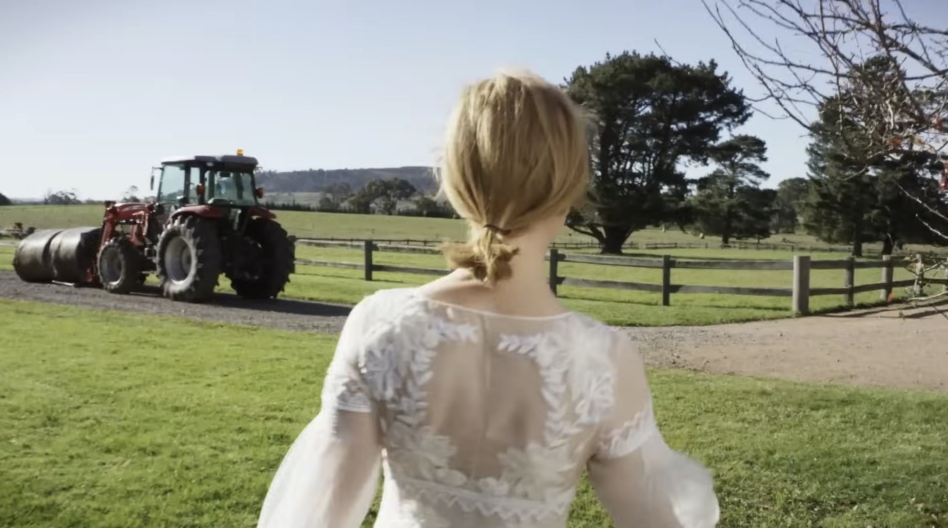A red tractor hauling hay rolls down the drive as Nicole Kidman looks on, offering a glimpse into the day-to-day workings of the farm beyond its picturesque calm. From a video dated July 20, 2015. | Source: YouTube/Vogue