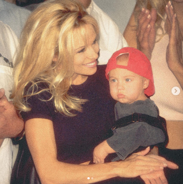 A nostalgic family throwback captures Pamela Anderson smiling down adoringly at her baby son Brandon Thomas Lee, who looks out wearing a backwards red baseball cap. Looking back on raising her boys with enduring devotion and pride, she reflected on their lifelong bond with touching gratitude: "There have been many ups and downs, and they have proved time again their resilience and strength. My love story is not complete without them. 🤍" | Source: Instagram/pamelaanderson