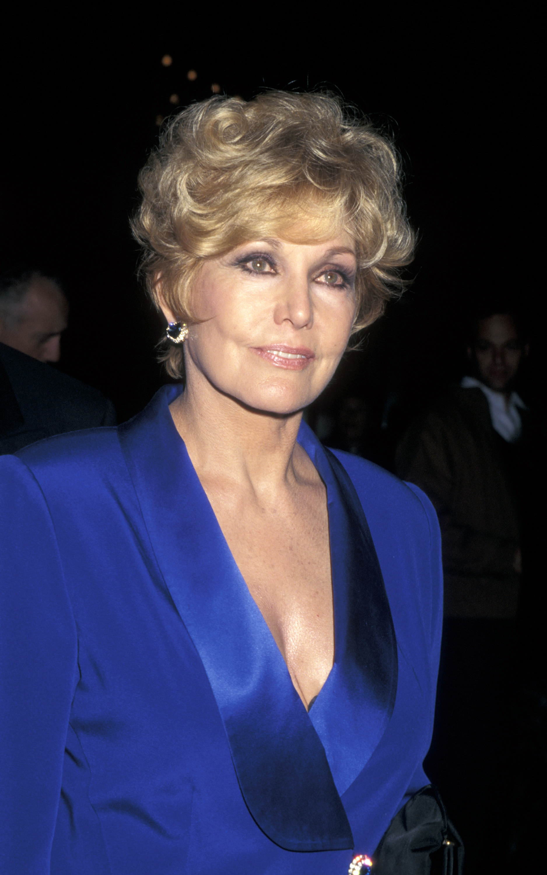 Kim Novak attends the New York premiere of the newly restored Vertigo, wearing a striking blue satin outfit with a plunging neckline. | Source: Getty Images