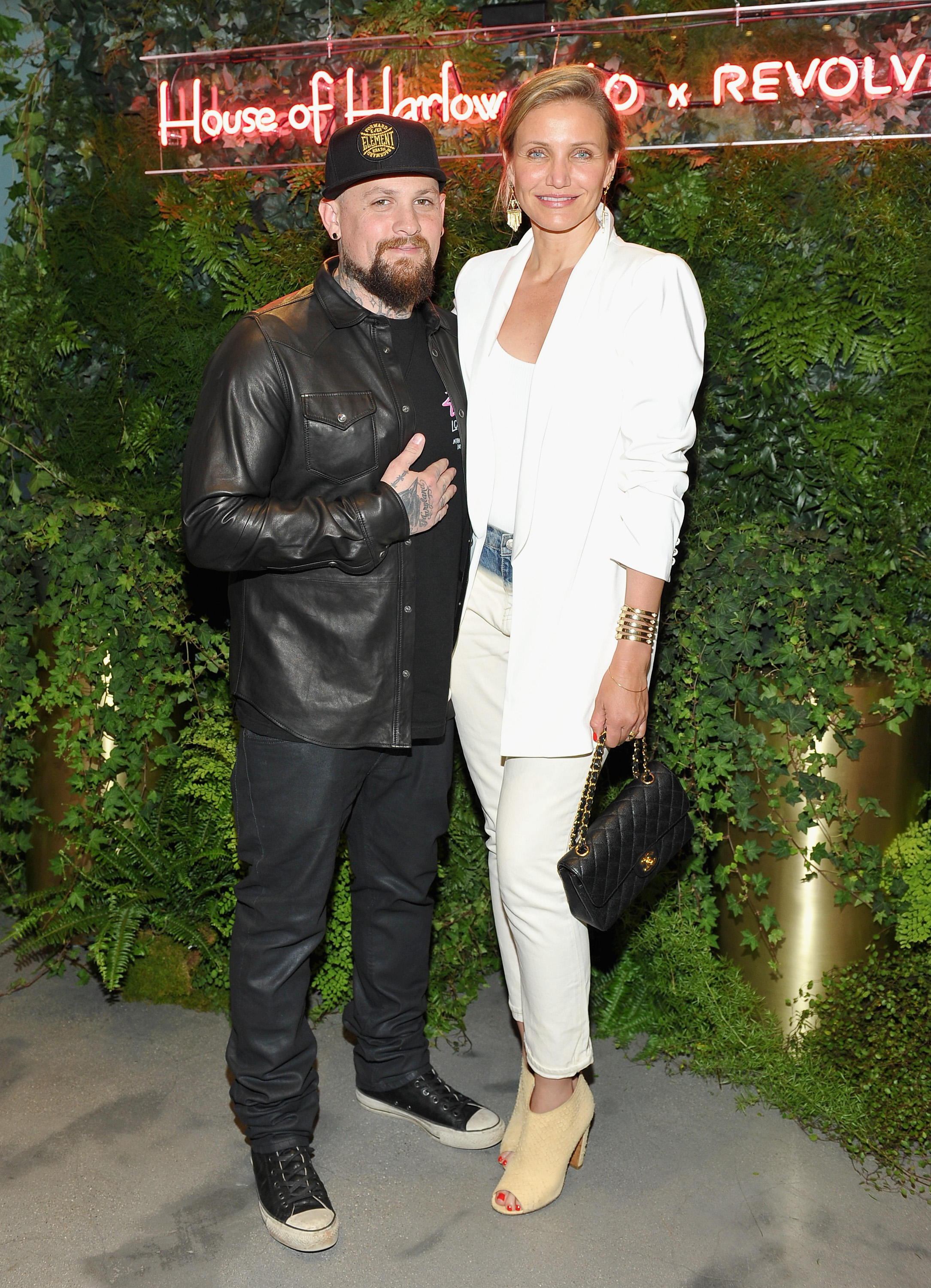 Stepping into the spotlight together, Cameron Diaz and Benji Madden attended the House of Harlow 1960 x REVOLVE event on June 2. Cameron stunned in a sleek white blazer and matching trousers with a classic Chanel bag, while Benji kept his signature rocker style in a leather shirt and sneakers. The couple posed arm in arm against a lush green backdrop, blending Hollywood chic with rock-and-roll edge.