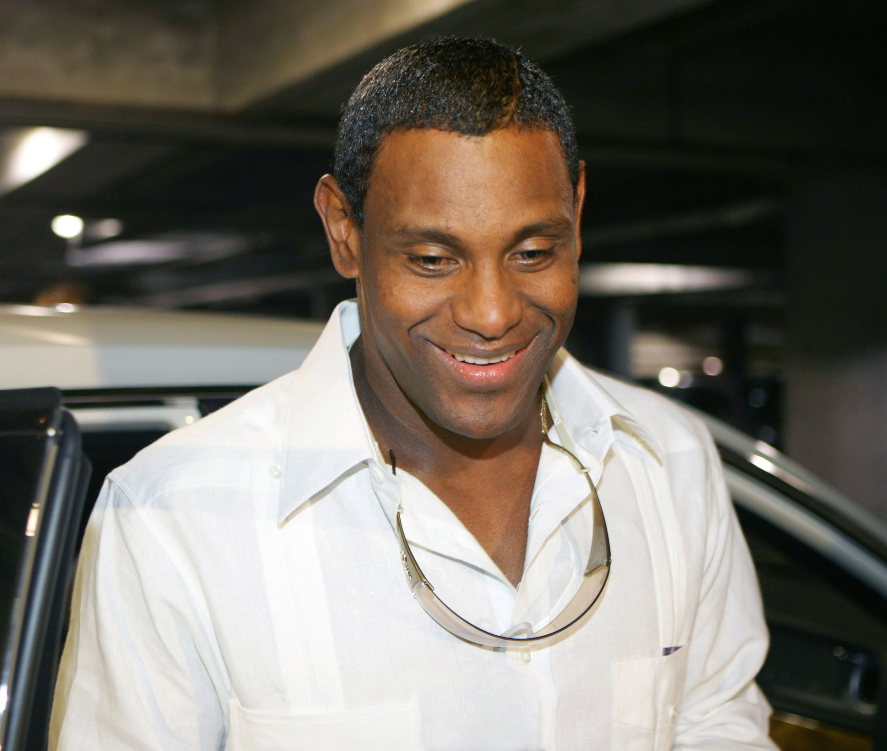 Sammy Sosa smiled while attending Gloria Estefan's "Live & Re-Wrapped" tour at American Airlines Arena in Miami, Florida, on October 9, 2004. Wearing an open-collar white shirt with sunglasses hanging across his chest, the Chicago Cubs star was photographed away from the baseball field during his final season with the team, months before his long association with the franchise ended. He continued his Major League Baseball career elsewhere the following year.