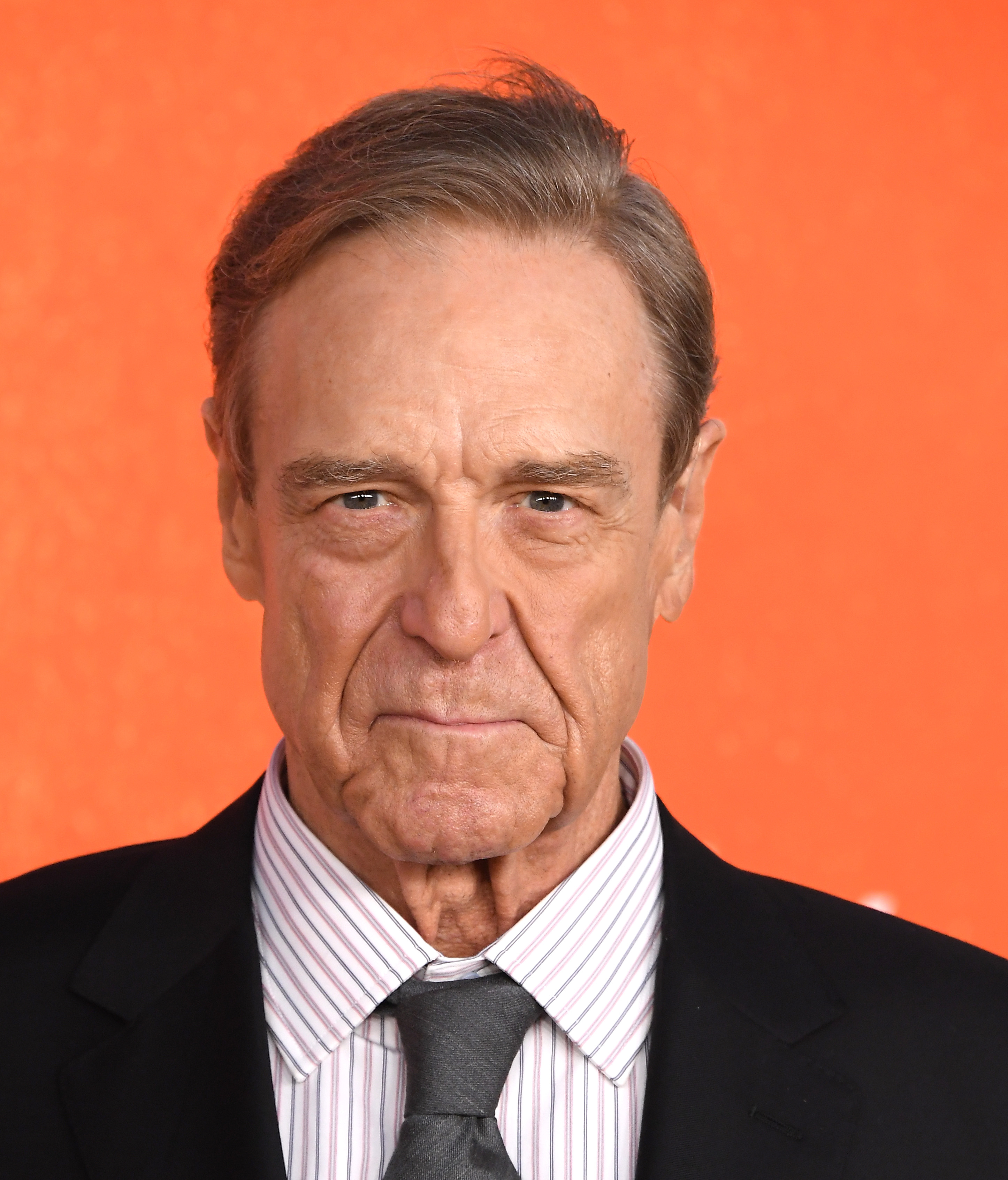 A close-up portrait from the "Digger" premiere puts the focus on Goodman's face as he poses in a striped shirt, gray tie, and black suit. The tighter view captures his leaner facial features, one of the changes viewers later discussed online.
