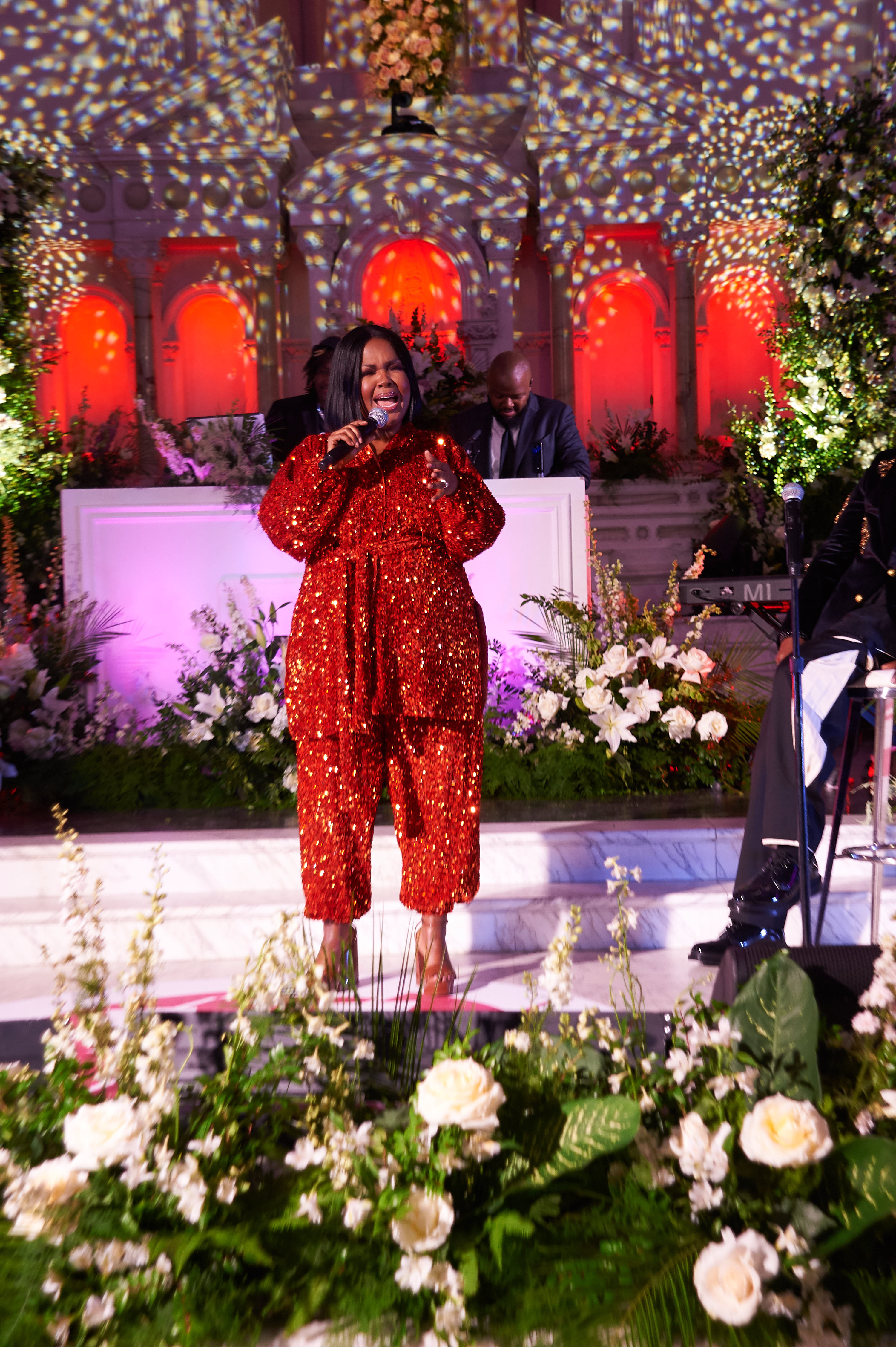 CeCe Winans performs in a bright red sequined outfit surrounded by floral arrangements during "Verzuz: Mary Mary Vz. BeBe and CeCe Winans" in Los Angeles, California, on April 17, 2022.