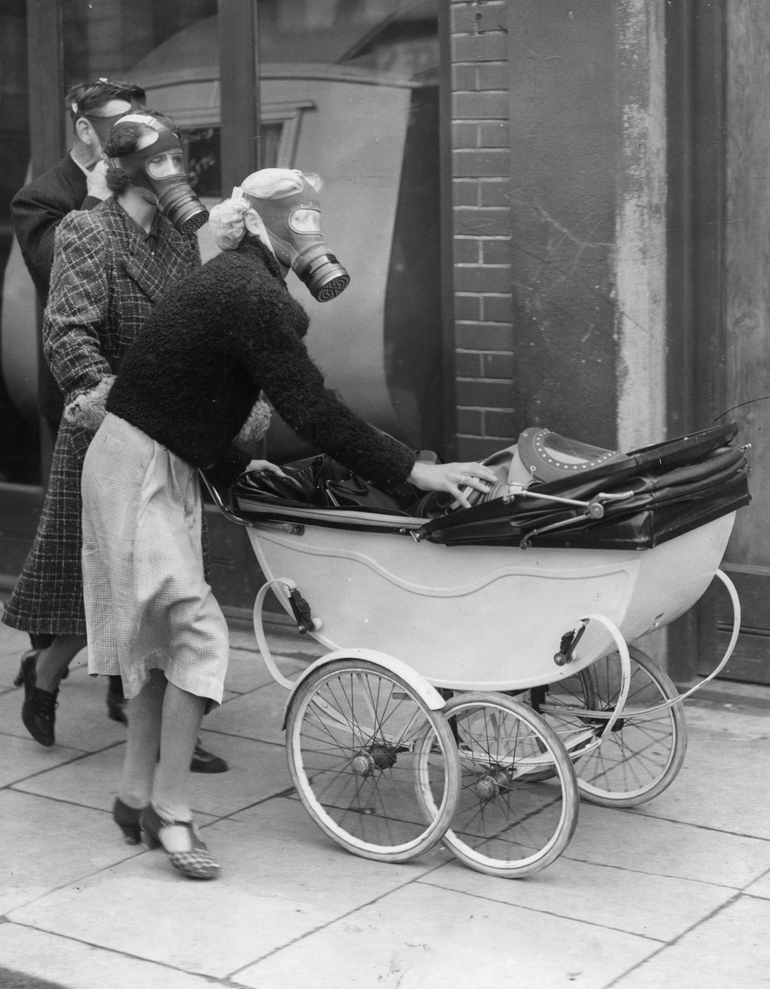 Mother fitting a gas mask on her baby during a WWII drill | Source: Getty Images