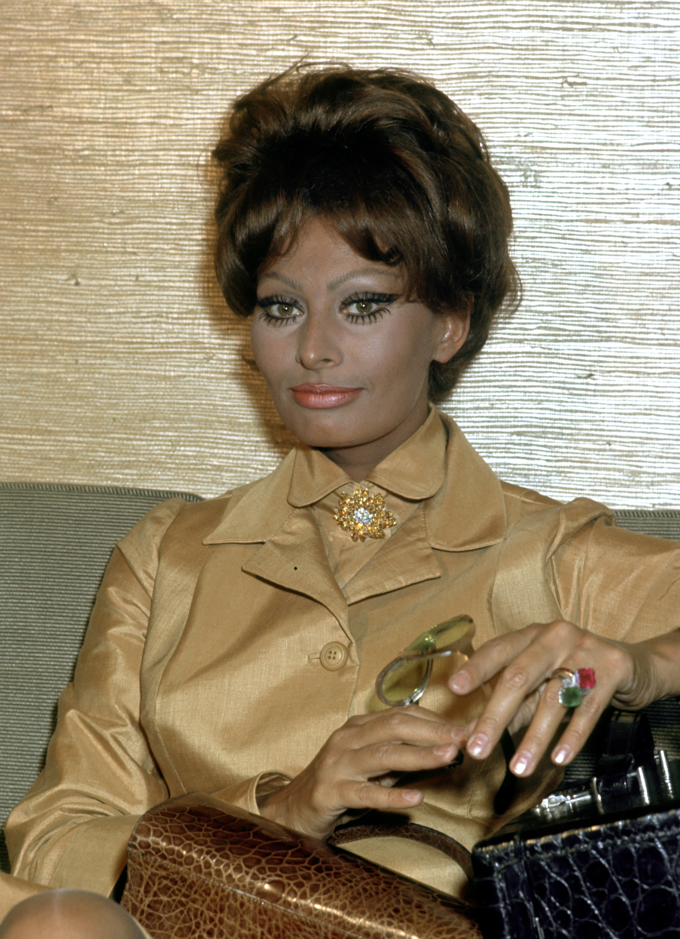 Sophia Loren photographed at Rome Airport, seated with a handbag and wearing a polished, formal ensemble | Source: Getty Images