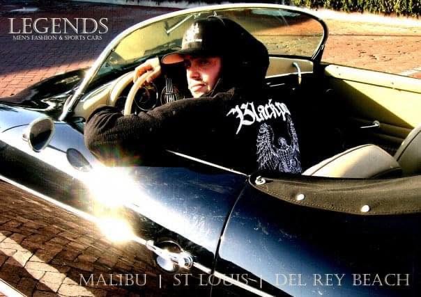 The former child star sits behind the wheel of a blue convertible in a promotional photo for Legends Men's Fashion & Sports Cars, reflecting his career shift from Hollywood to the luxury car business.