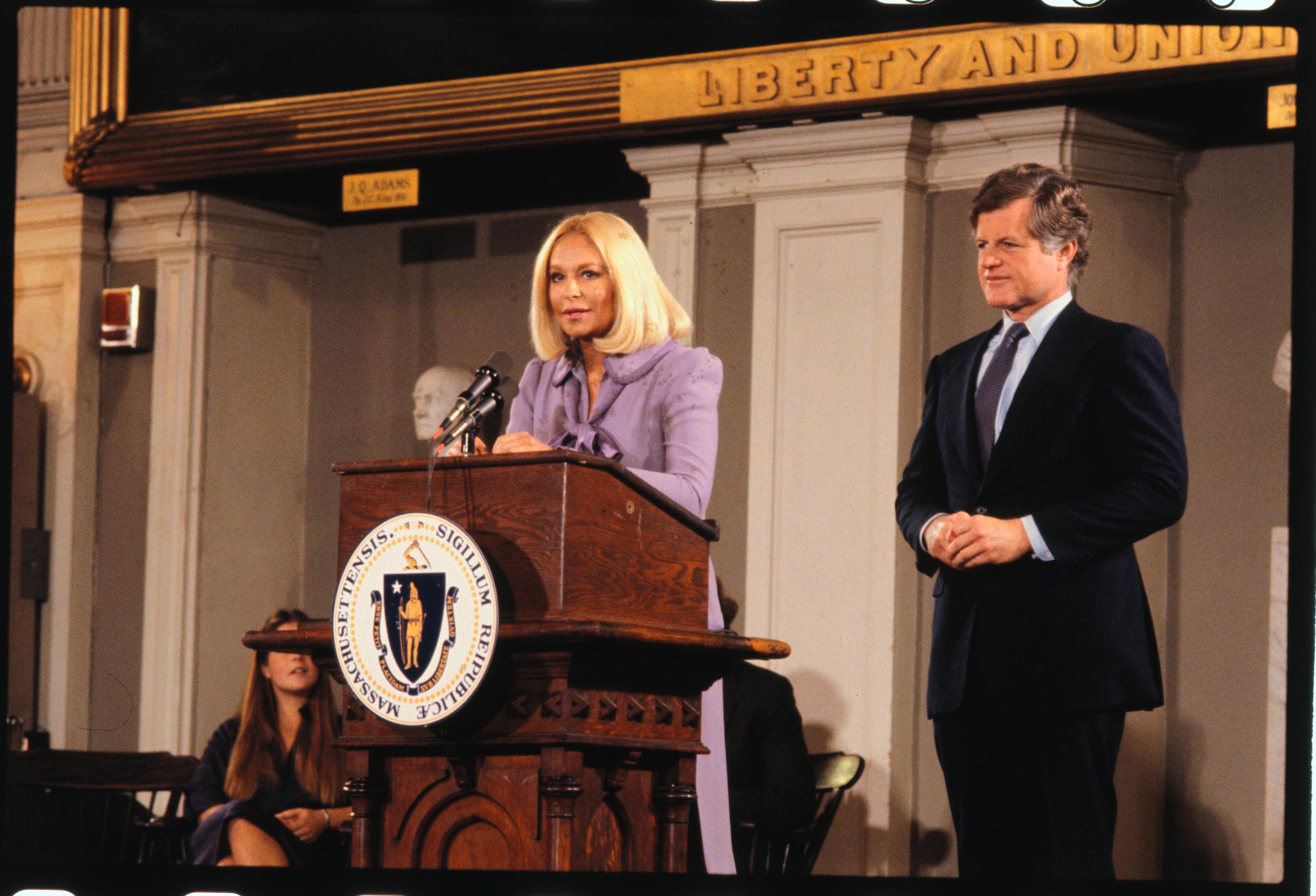 Joan Kennedy speaking with reporters as Ted Kennedy looks on in 1979. | Source: Getty Images