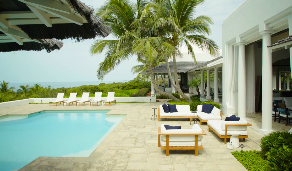 The swimming pool terrace sits close to the island's waterfront. Its furnishings were selected to complement the home's relaxed and understated tropical design. | Source: YouTube/Architectural Digest