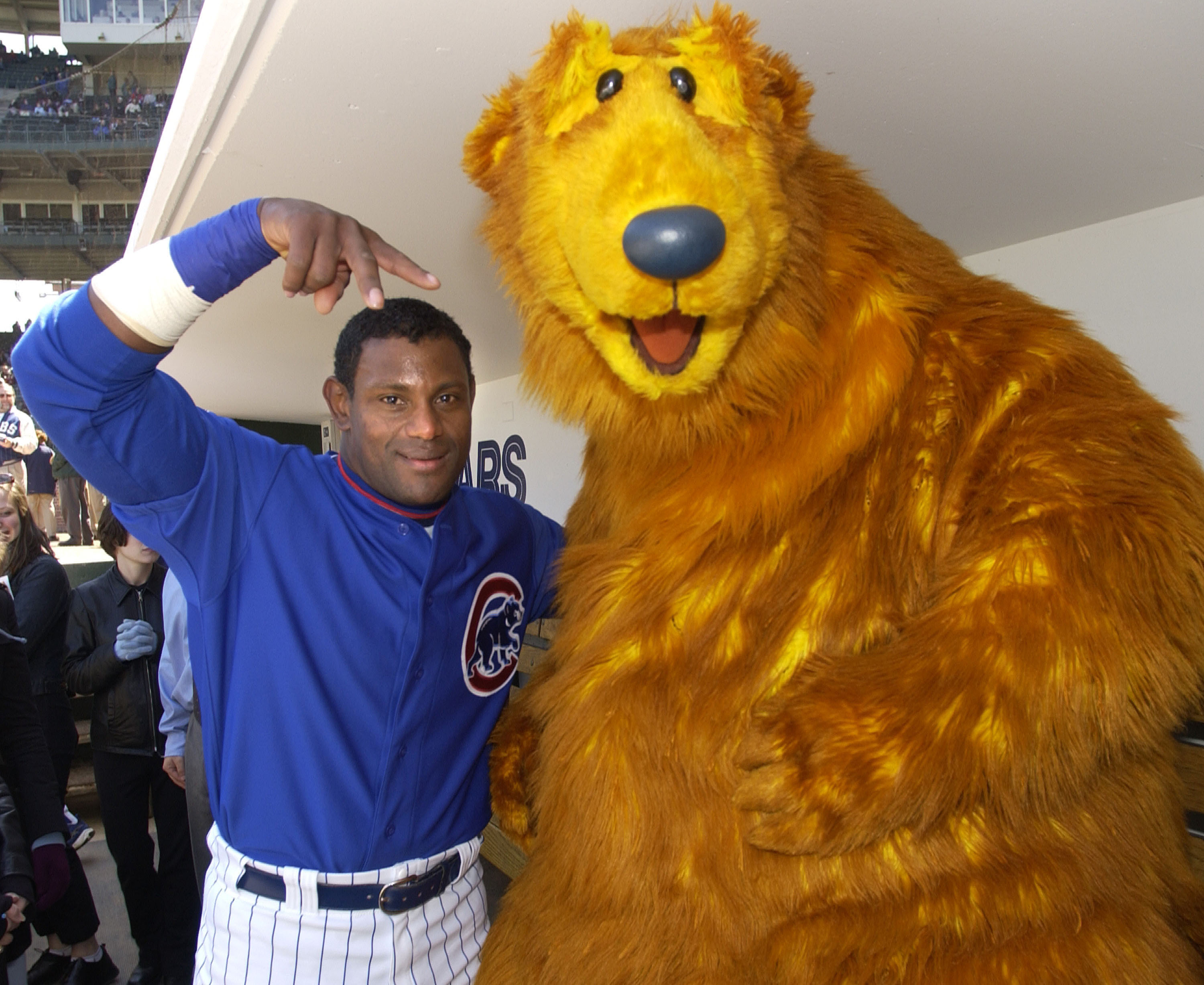 Sammy Sosa posed alongside Bear from "Bear in the Big Blue House" before the Chicago Cubs played the Los Angeles Dodgers at Wrigley Field on April 26, 2002. Dressed in his Cubs uniform, Sosa gestured toward the children's television character, who visited Chicago while promoting the charity Voices for Illinois Children and raising awareness during Child Abuse Prevention Month, bringing the campaign directly into the ballpark before that day's game.
