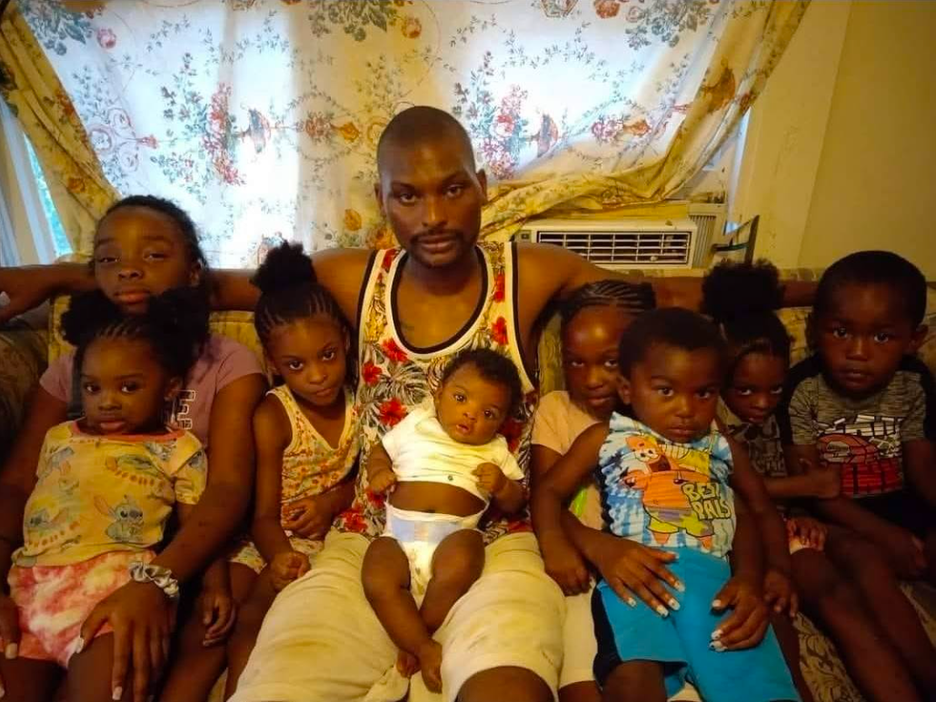 A closely gathered family moment showing Shamar Elkins seated at the center with his children and their cousin surrounding him. | Source: Facebook/Shamar Elkins