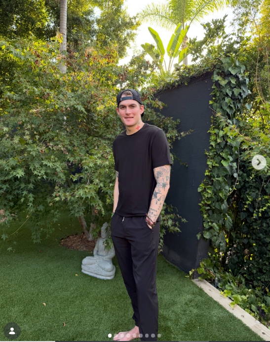 In a post shared on August 5, 2026, 27-year-old Presley Gerber stood barefoot on a lush green lawn beside a Buddha statue and foliage, keeping things laid-back in an all-black casual ensemble consisting of a crewneck T-shirt, matching trousers, a backwards baseball cap, and beaded wristwear that highlighted his sleeve and neck tattoos. | Source: Instagram/presleygerber