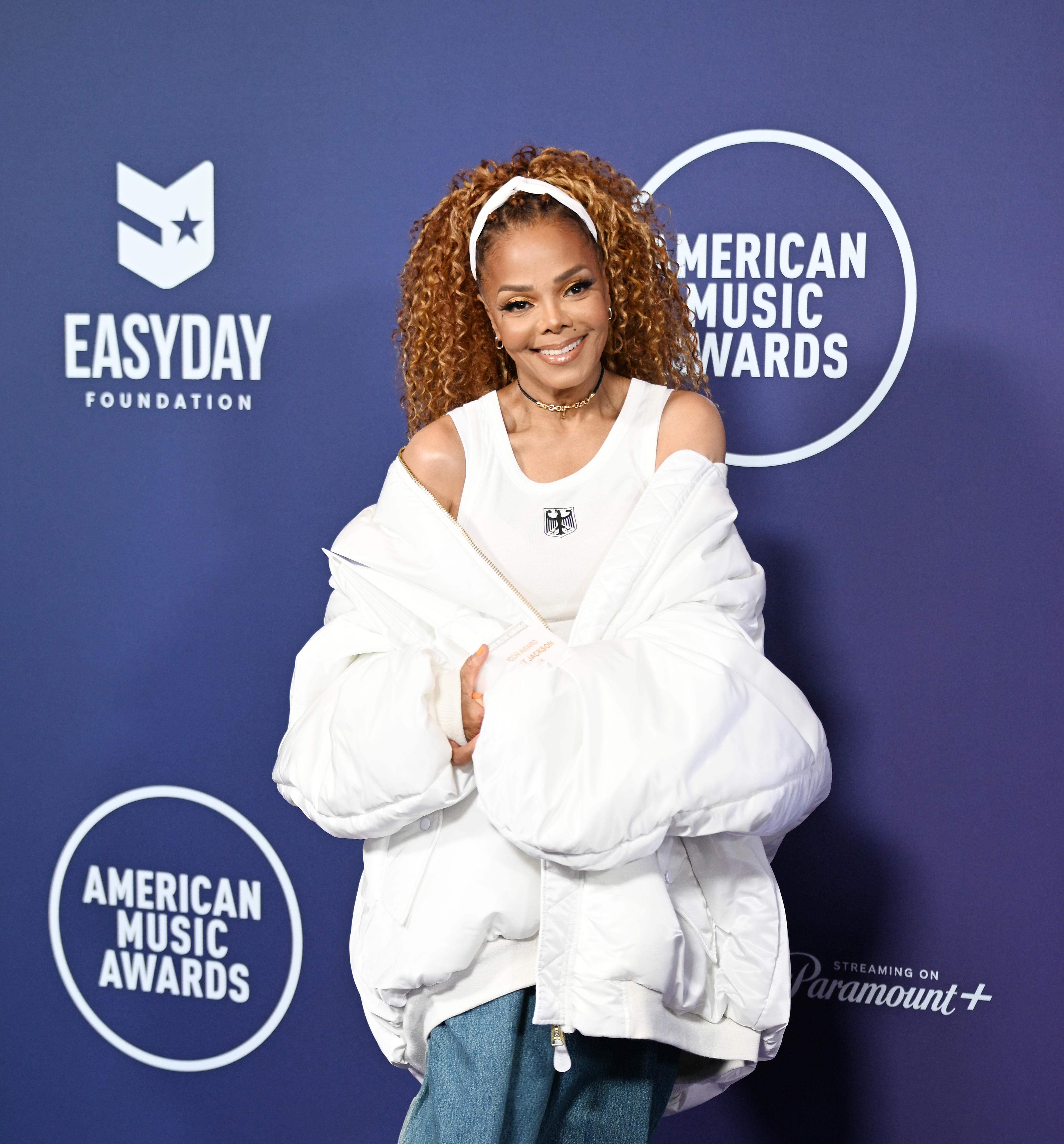 Against a bold AMA backdrop, Jackson's wide-legged jeans and chunky sneakers ground her red carpet look in ‘90s nostalgia with a modern twist.