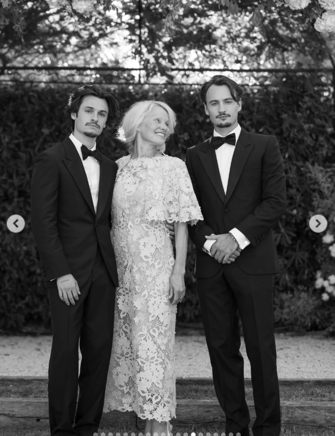 Pamela beamed between her sons, Brandon and Dylan, in a delicate lace dress with a cape-like overlay, as the brothers looked sharp in classic black tuxedos. | Source: Instagram/thierryjoubertphotography