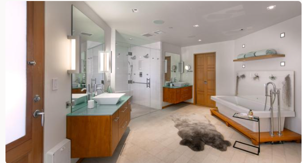 The spacious bathroom features a freestanding bathtub, a glass-enclosed shower, and wooden vanities with green countertops. | Source: Redfin