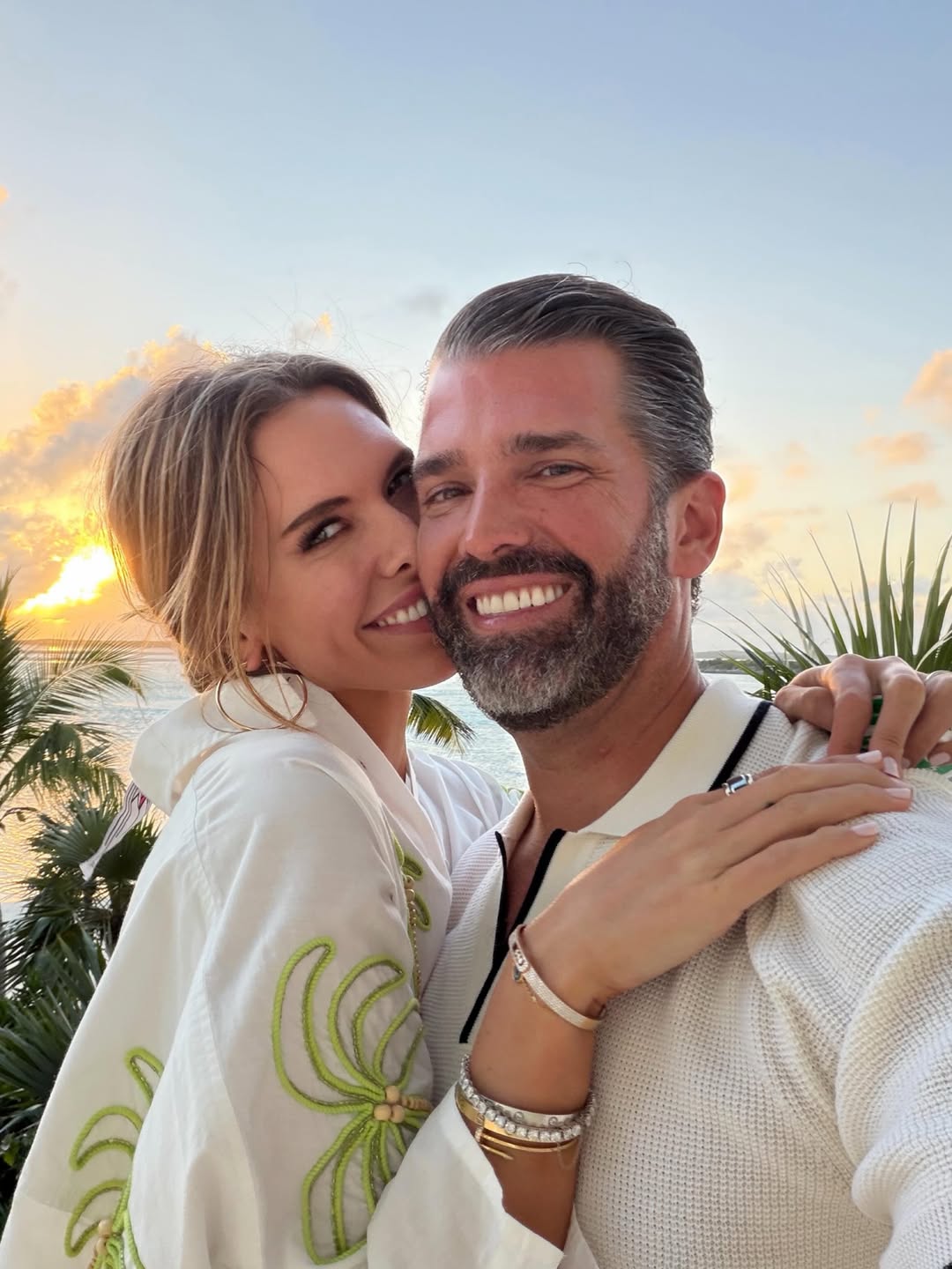 Bettina Anderson leans close to Donald Trump Jr. as the couple beams for a sunset selfie overlooking the water.