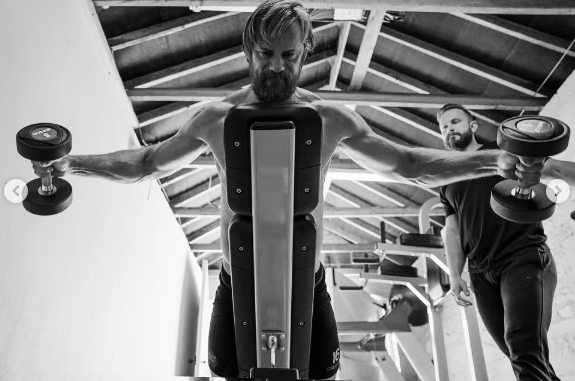 Alexander Skarsgård worked through a dumbbell exercise as trainer Magnus Lygdback watched closely during his physical preparation for "The Northman." The training photo was shared in a September 28, 2024, post. | Source: Instagram/aidanmonaghanphotographer