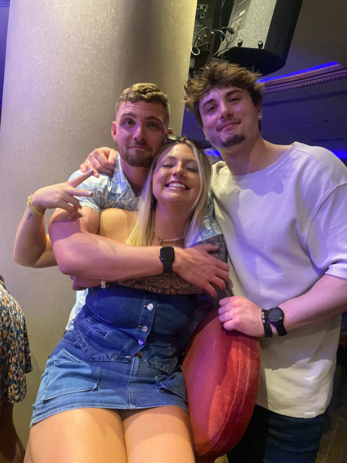 In a lively, dimly lit setting, Jack Pugh stands close with two friends, their arms wrapped around each other in an easy, unfiltered embrace. | Source: Facebook/KennaLynMcClelland