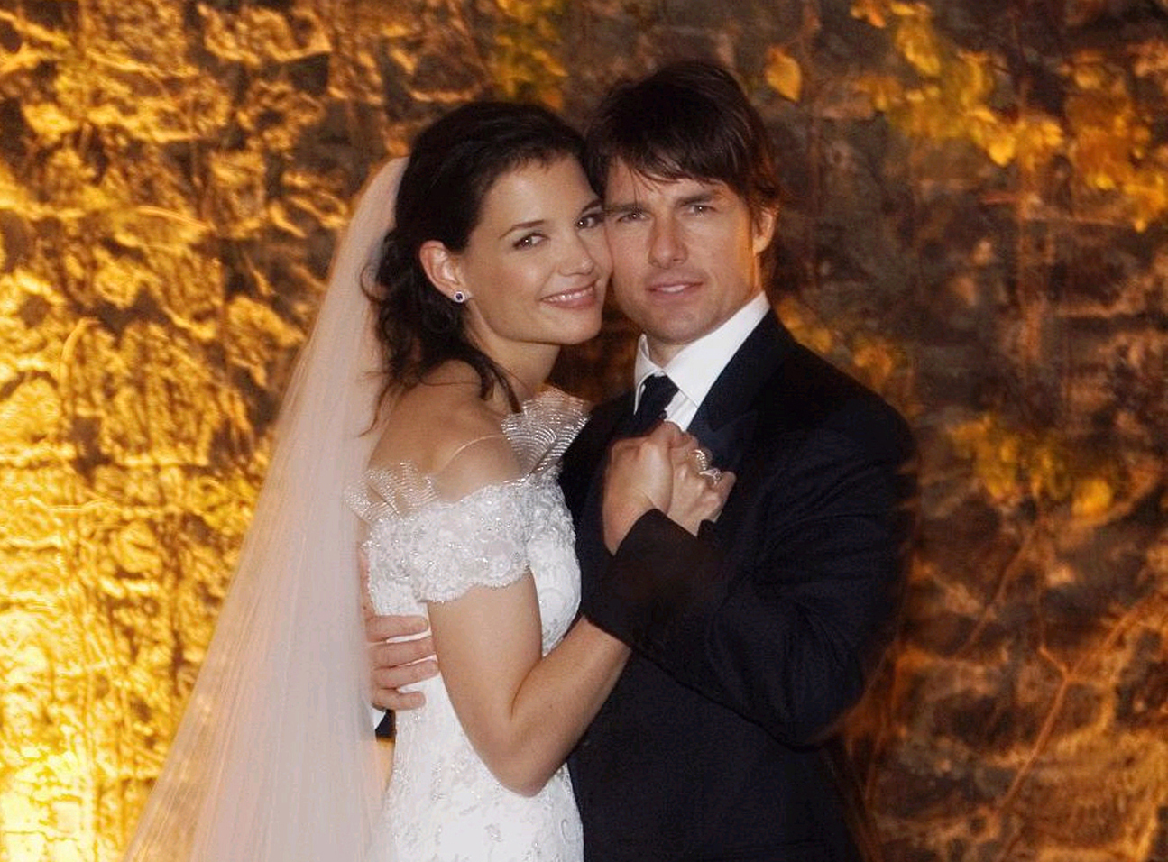 In their wedding portrait, the couple posed lovingly against a warm, romantic backdrop, that captured a timeless moment from their wedding day. Katie Holmes radiated classic beauty in a lace-embellished off-the-shoulder gown and flowing veil as she embraced Tom Cruise.