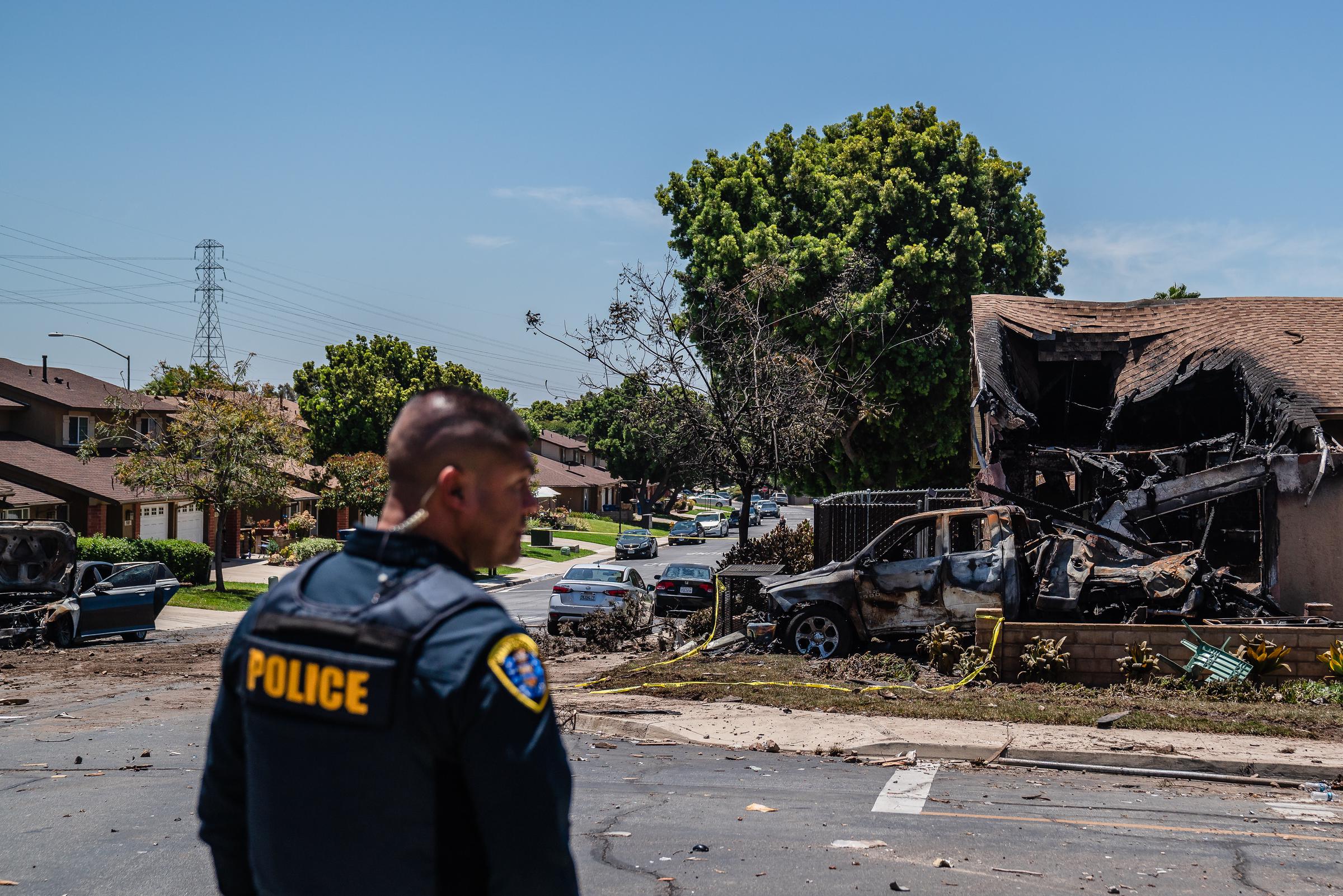 A police officer surveys the scene after a small plane crashed into a San Diego home, causing heavy fire damage on May 22, 2025 | Source: Getty Images