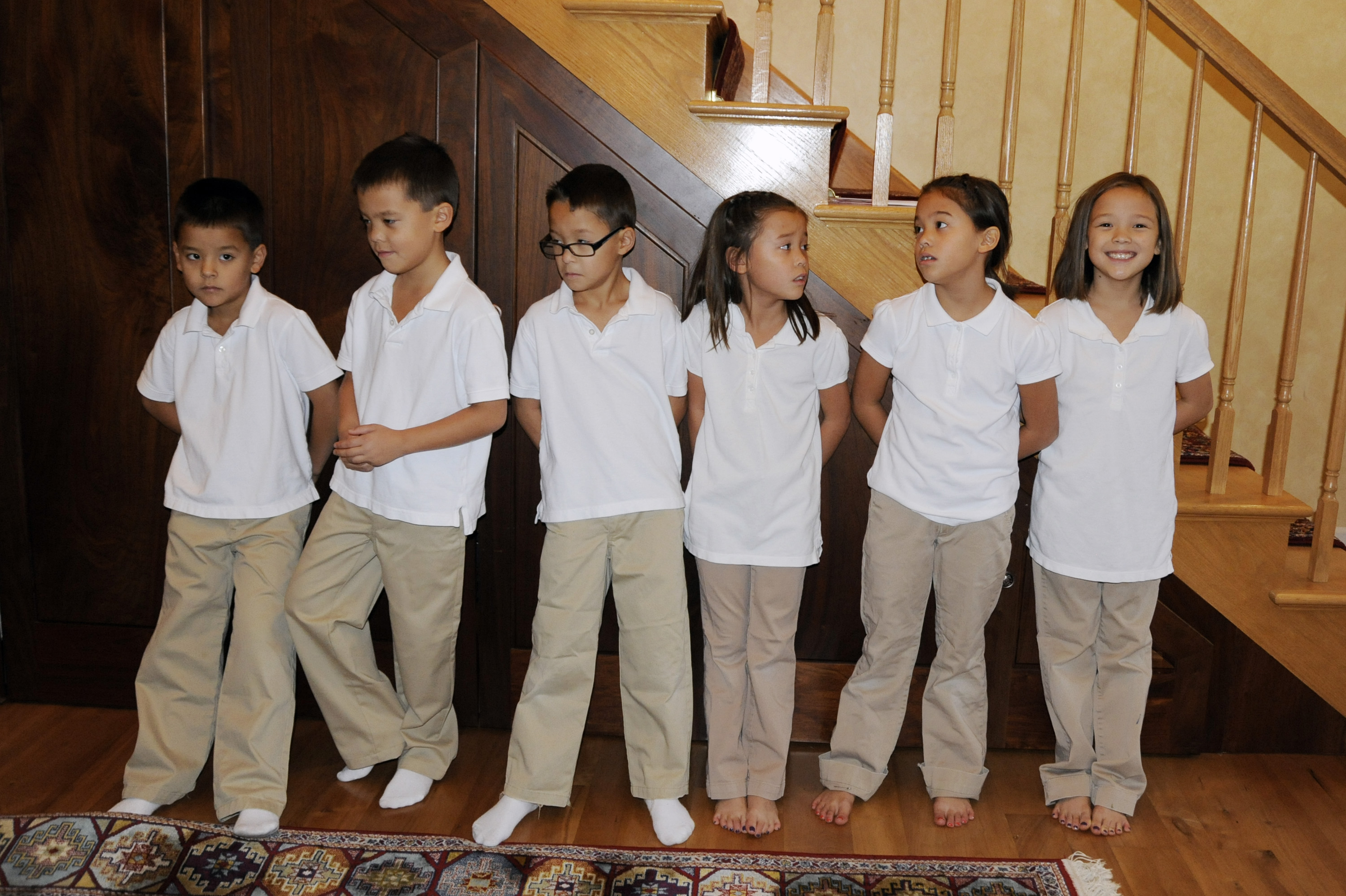 The Gosselin children pose together in matching white polo shirts and khaki pants beside the wooden staircase inside their Pennsylvania home. Ashley alleged that Kate limited the children's school outfits to reduce laundry and described the household's interactions as lacking warmth.