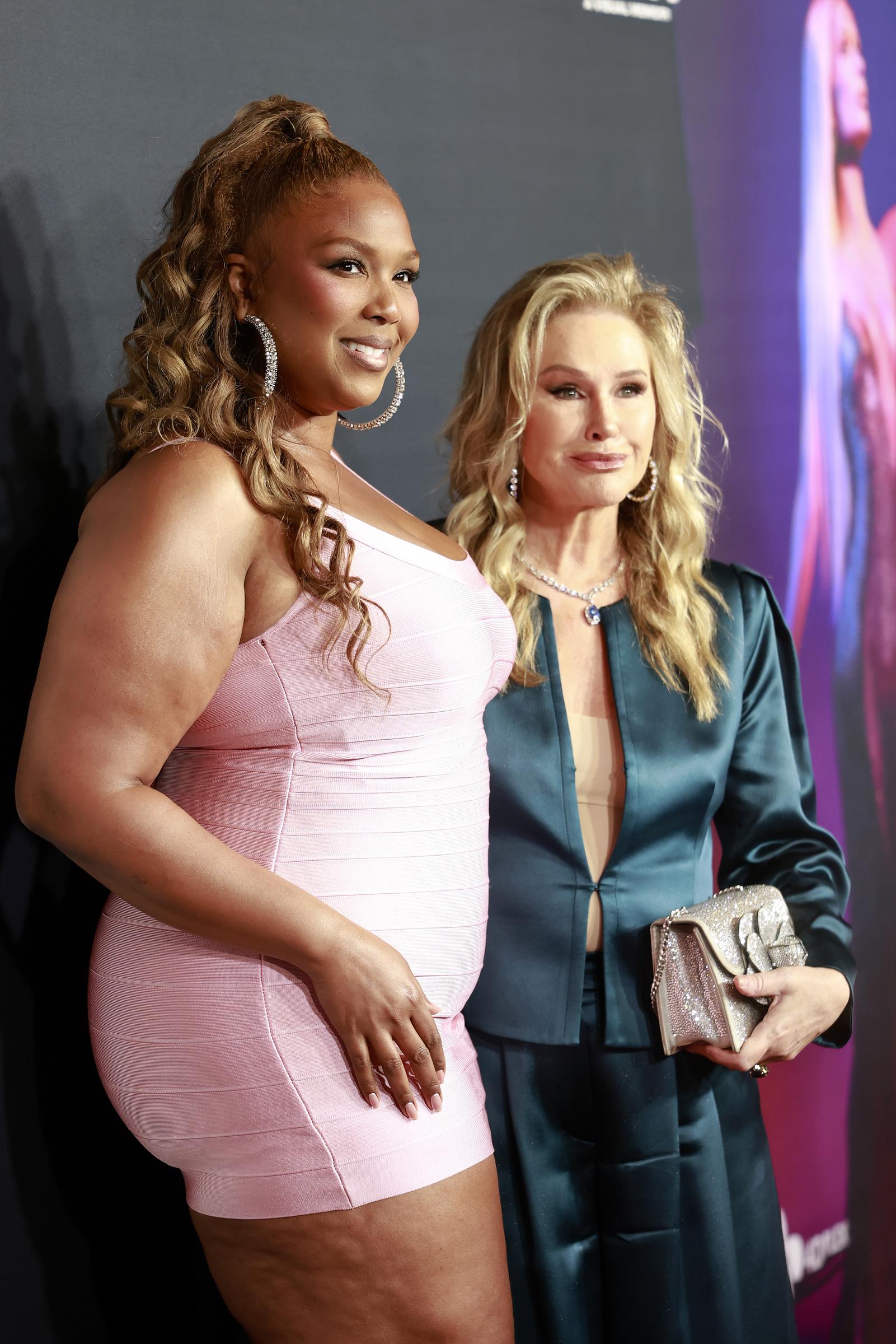Lizzo poses side-by-side with Kathy Hilton, offering a clear profile of her visibly flatter stomach and narrowed hips. The snug dress outlines her trimmed-down curves with no visible shapewear or compression underneath.