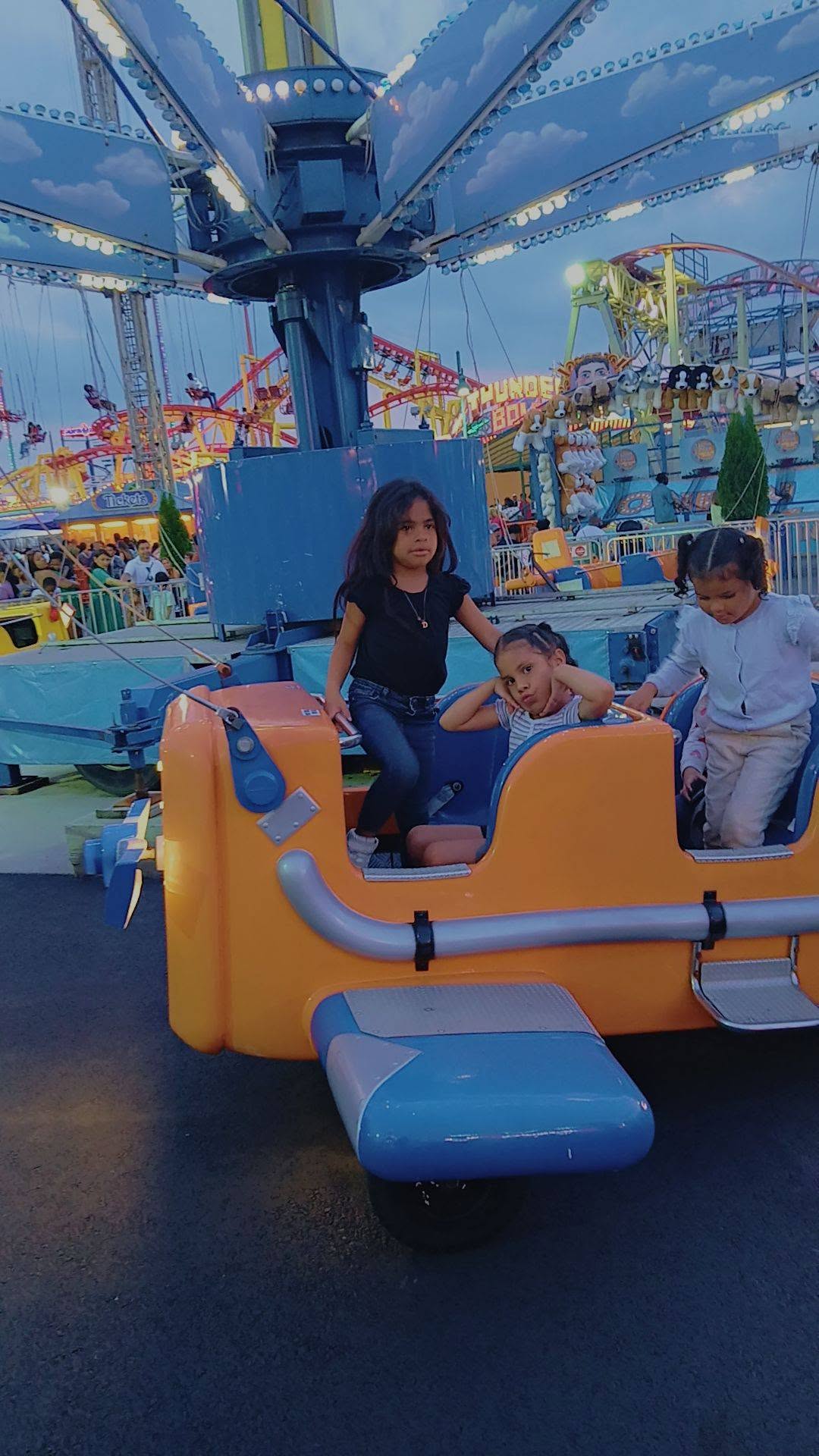 Eddimar Paola Hernández Chacón struck a playful pose with her hands behind her head while enjoying an airplane ride alongside two young companions at an amusement park. Dressed in a striped top, Eddimar sat comfortably in the bright orange and blue ride car, surrounded by the colorful lights, carnival attractions, and roller coasters of the bustling fairgrounds. | Source: Facebook/Morena Esa