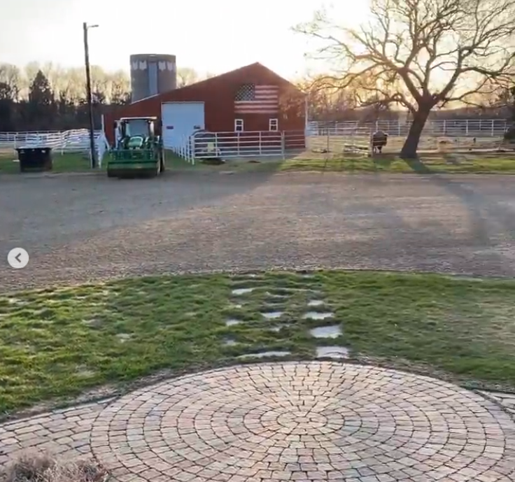 In warmer weather, the ranch setting becomes clearer. A red barn, white fencing, farm equipment, and livestock sit beyond the lawn and gravel drive. | Source: Instagram/sdbryonnoem