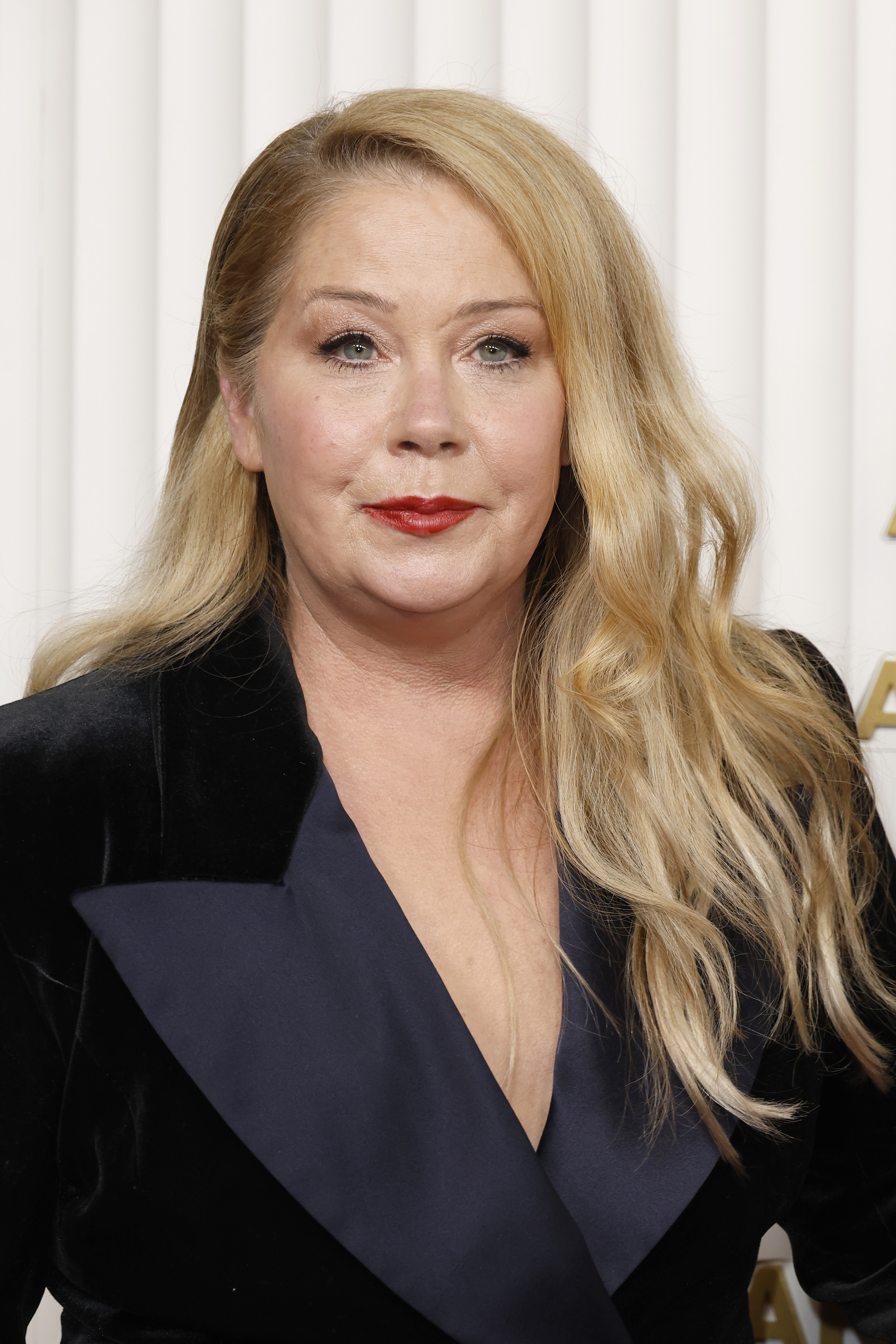Christina Applegate attended the 29th Annual Screen Actors Guild Awards at the Fairmont Century Plaza on February 26, 2023, in Los Angeles, California. The actress stunned in a sleek black velvet trench-style gown featuring dramatic satin peak lapels, wearing her long blonde tresses in loose, textured waves paired with defined lashes and a classic red lipstick. | Source: Getty Images