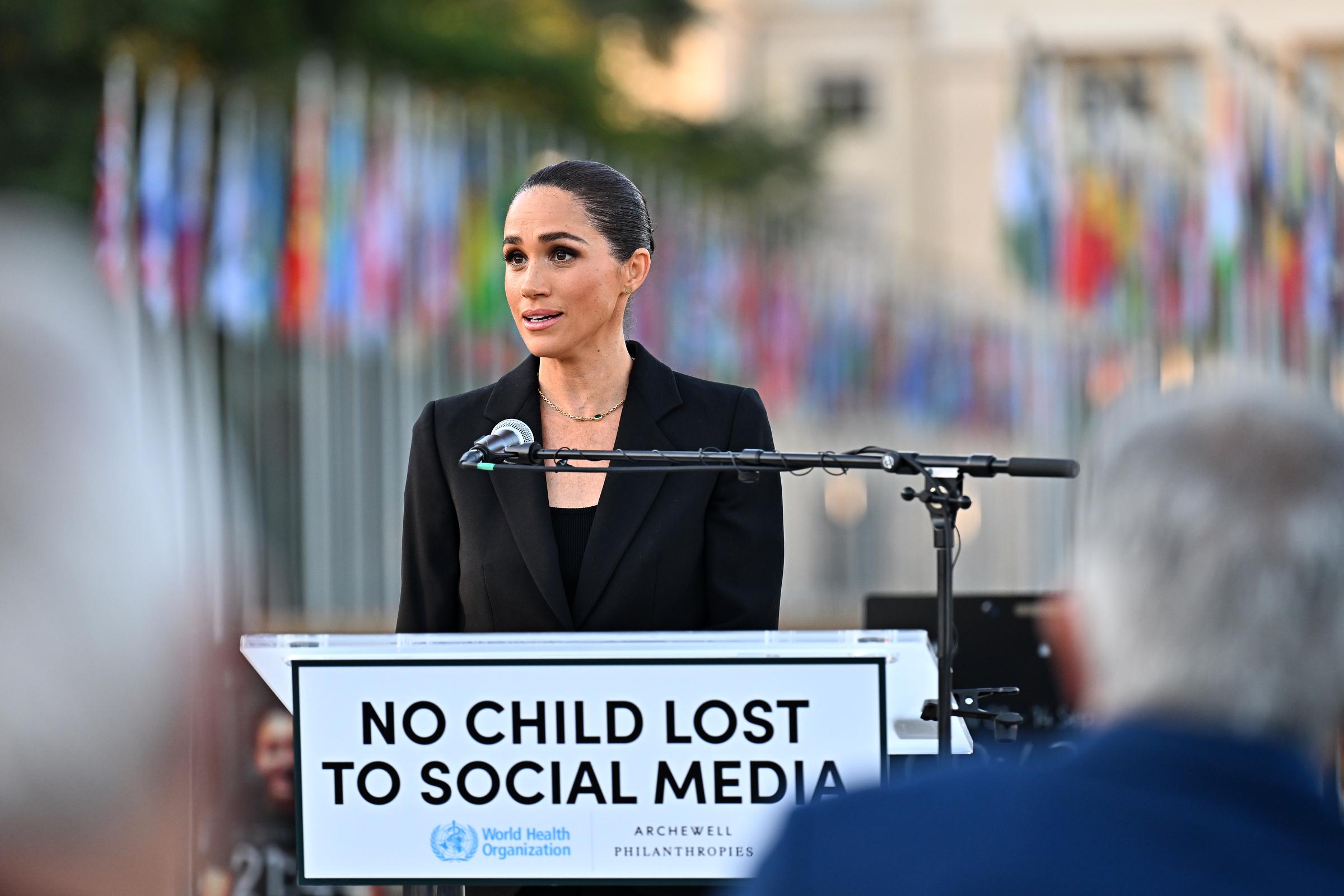 Meghan spoke at a podium in May 2026 during an event highlighting the impact of social media on children, wearing a black blazer and a gold necklace. | Source: Getty Images