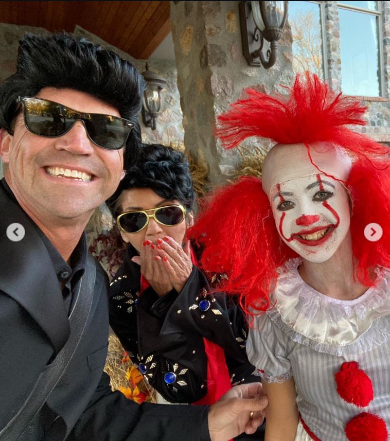 A lighthearted moment with a spooky twist—Bryon grins beside a bright red-haired clown, while Kristi playfully hides a laugh, capturing the fun of a Halloween night full of surprises. | Source: Instagram/sdbryonnoem